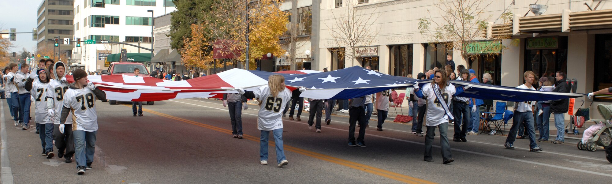 MOUNTAIN HOME AIR FORCE BASE, Idaho - Suzanne Ramos, Mrs. Kuna, helps the Kuna freshman football team carry a giant flag in the Boise Veterans Day parade Nov. 8. More than 2,000 military members walked in the parade representing all the branches of the armed forces. (U.S. Air Force photo/ Airman Debbie Lockhart)