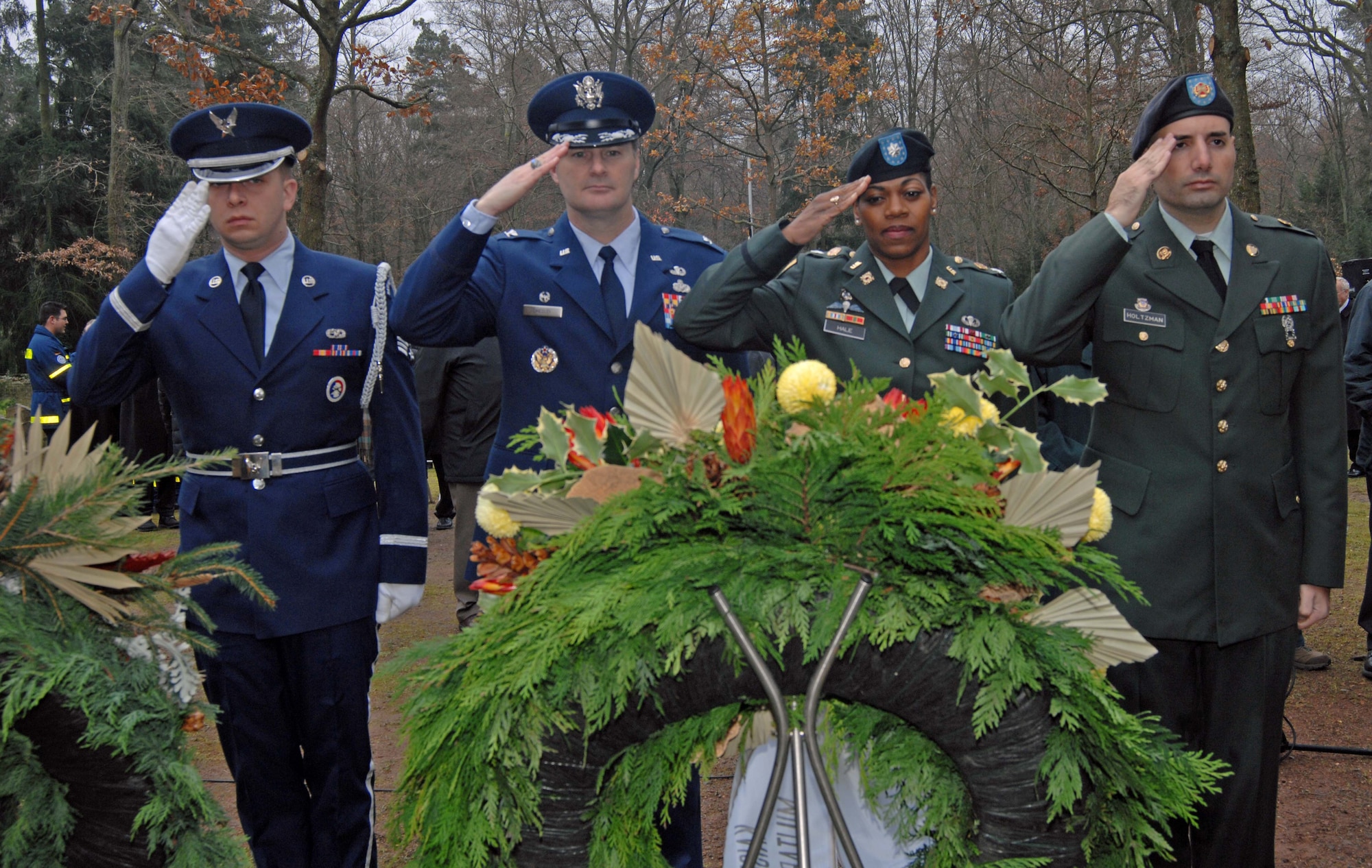 Senior Airman Brian Lapiska, from the 86th Airlift Wing's 1st Combat Communications Squadron, Air Force Col. Gary Chesley, the 435th Air Base Wing's Civil Engineer Group commander, Army Lt. Col. Mechelle Hale, the U.S. Army Garrison Kaiserslautern commander, and Spc. Vincent Holtzman, from the garrison's Directorate of Human Resources, render a salute during the Kaiserslautern military community wreath-laying ceremony Sunday during the German National Day of Mourning at the Soldiers' Monument in the Kaiserslautern Cemetery. More than 150 people from several different nationalities attended the ceremony. The National Day of Mourning or Volkstrauertag is a public holiday in Germany that is observed two Sundays before the first Advent - the Sunday that is in the period from Nov. 13 to 19. This German holiday is similar to the United States' "Veteran's Day," except that it commemorates all victims who died during wars. It was first observed in Germany in 1952. The city of Kaiserslautern and the German Association of War Graves have held the Volkstrauertag wreath-laying ceremony at the Soldiers’ Monument in the Kaiserslautern Cemetery for 25 years. The ceremony usually consists of about 10 wreath presentations, one of which is from the Kaiserslautern military community where an Airman and Soldier will present the wreath and alongside an Air Force and Army officers will render a salute. The U.S. Army Garrison Kaiserslautern has participated in this ceremony since it was established in 1992. With two eternal flames, the Soldiers’ Monument watches over military graves from World War I and World War II. U.S. Army photo by Christine June, USAG Kaiserslautern.
