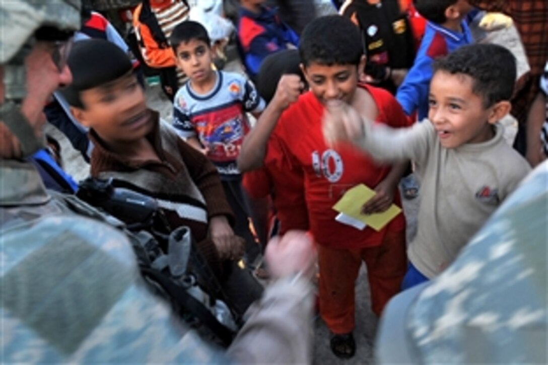 U.S. Air Force airmen speak with Iraqi children during a patrol with Iraqi police in the Shurta Market of the Al-Bayaa district of Baghdad, Iraq, Nov. 14, 2008. The airmen are assigned to 732nd Expeditionary Security Forces Squadron.