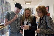 Aaron Mankin shows pictures of his children to Operation Mend Coordinators Melanie Gideon, for UCLA, and Lisa Gustafson, for Brooke Army Medical Center, at UCLA Medical Center Nov. 18 before Mankin's 12th surgery at the hospital.  Mankin was the first wounded service member to take advantage of Operation Mend, a partnership between the U.S. military and UCLA Medical Center, through which UCLA provides world-class plastic reconstructive surgeries to disfigured service members. (Official U.S. Marine Corps photo by Staff Sgt. Ethan E. Rocke)