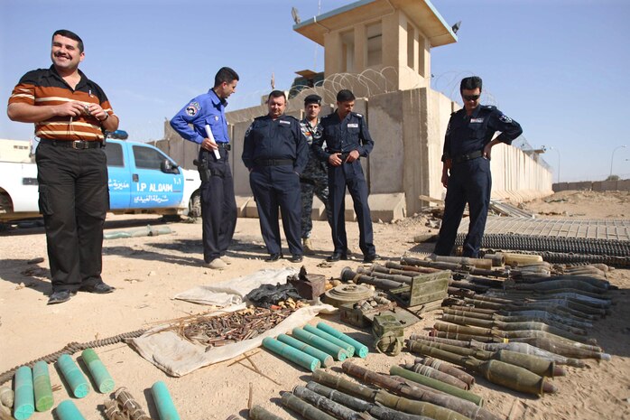 1st Lt. Faysal Sakit Shab (left), intelligence officer, National Iraqi Intelligence Agency, and police officers from Ubaydi, Iraq, look at a portion of the ordnance removed from a field near the city Nov. 19.  The weapons cache was discovered Nov. 14 following an investigation by the Iraqi Police of a rocket attack against Combat Outpost Ubaidi a week beforehand.::r::::n::