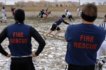 GRAND FORKS AIR FORCE BASE, N.D. –  5th Civil Engineer Squadron firefighters watch from the sidelines as their team hikes the ball and runs a play during the first –ever Dakota Bowl Championship flag football game here Nov. 15. The 5th CES Fire Dawgs won the game 27-21 in overtime. The idea of the Dakota Bowl/Cup came from the sports directors at both bases. They wanted to get the best teams in each intramural sport to have a one-game playoff to decide the best in North Dakota. (U.S. Air Force photo by Senior Airman Kelly Timney)