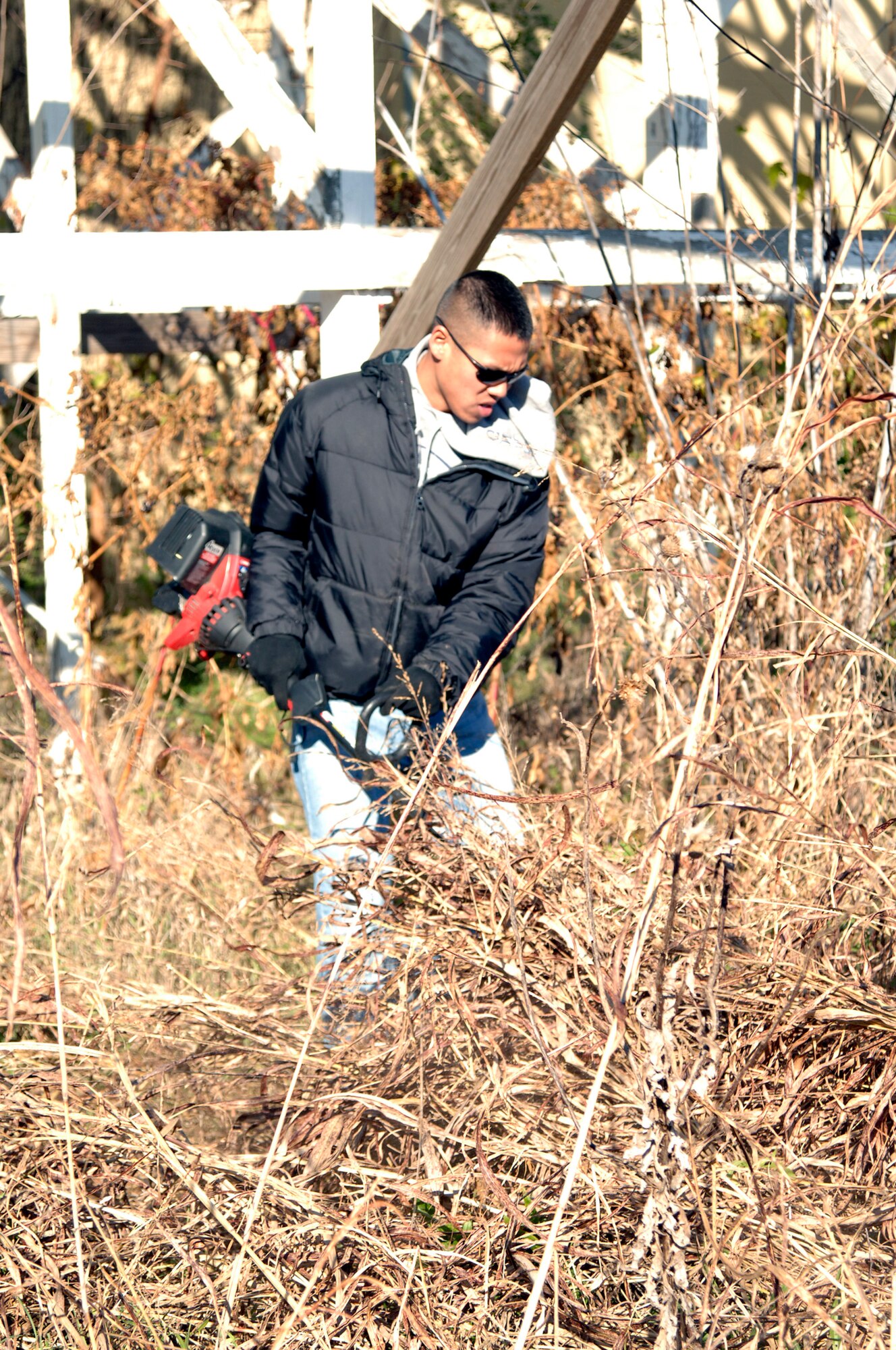 MCCONNELL AIR FORCE BASE, Kan. -- Senior Airman Francis Ngueyen, 184th Civil Engineer Squadron, cuts down weeds around a rollercoaster ride at Joyland Amusement Park in Wichita, Nov. 15.  More than 40 Team McConnell Airmen volunteered their time and equipment to help clean the park.   (Photo by Staff Sgt. Ronald Lafosse)
