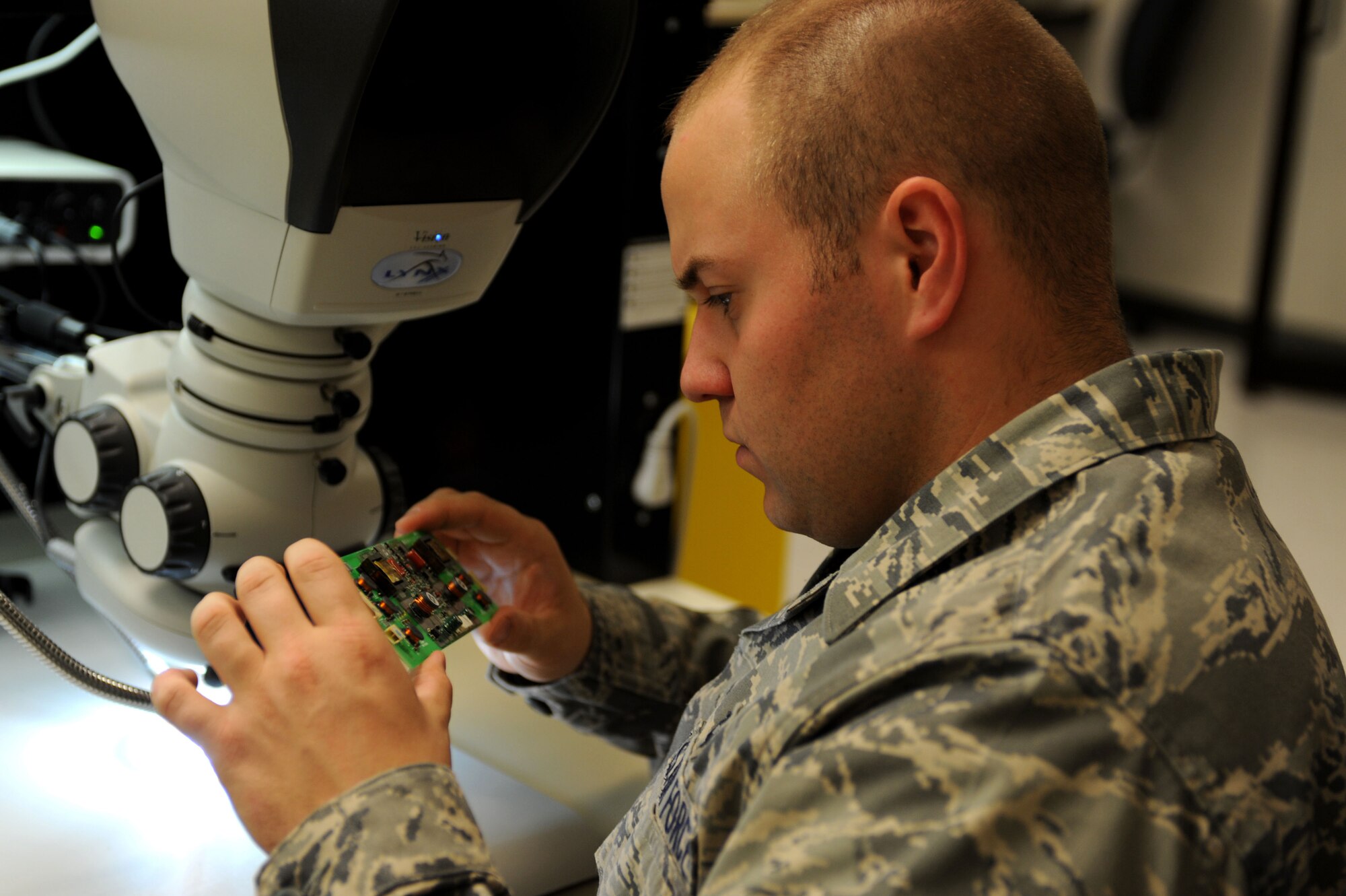 CANNON AIR FORCE BASE, N.M. -- Senior Airman Michael Harris, 27th Special Operations Maintenance Group, inspects a circuit card for an LCD monitor Nov. 5. Through the Air Force Repair Enhancement Program, Airmen work with advanced machinery to detect and repair malfunctioning circuits in equipment ranging from aircraft parts to office printers. The program saves the Air Force millions of dollars per year in equipment costs. (U.S. Air Force photo by Airman 1st Class Evelyn Chavez)