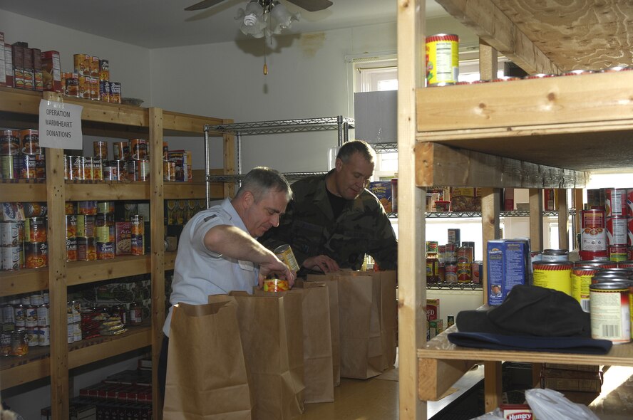 MINOT AIR FORCE BASE, N.D. -- Master Sgt. Guy Jencks (left), 5th Maintenance Squadron first sergeant, and Master Sgt. Todd Brown (right), 5th Maintenance Group first sergeant, put together a Thanksgiving food basket at the First Sergeant's Food Pantry here during Operation Warmheart Nov. 17. The food baskets will contain a complete Thanksgiving dinner and will be given out to Minot AFB families. The First Sergeant's Council conducts Operation Warmheart on an annual basis and this year will supply dinner to more than 180 Minot AFB families. (U.S. Air Force Photo by Senior Airman Joe Rivera)