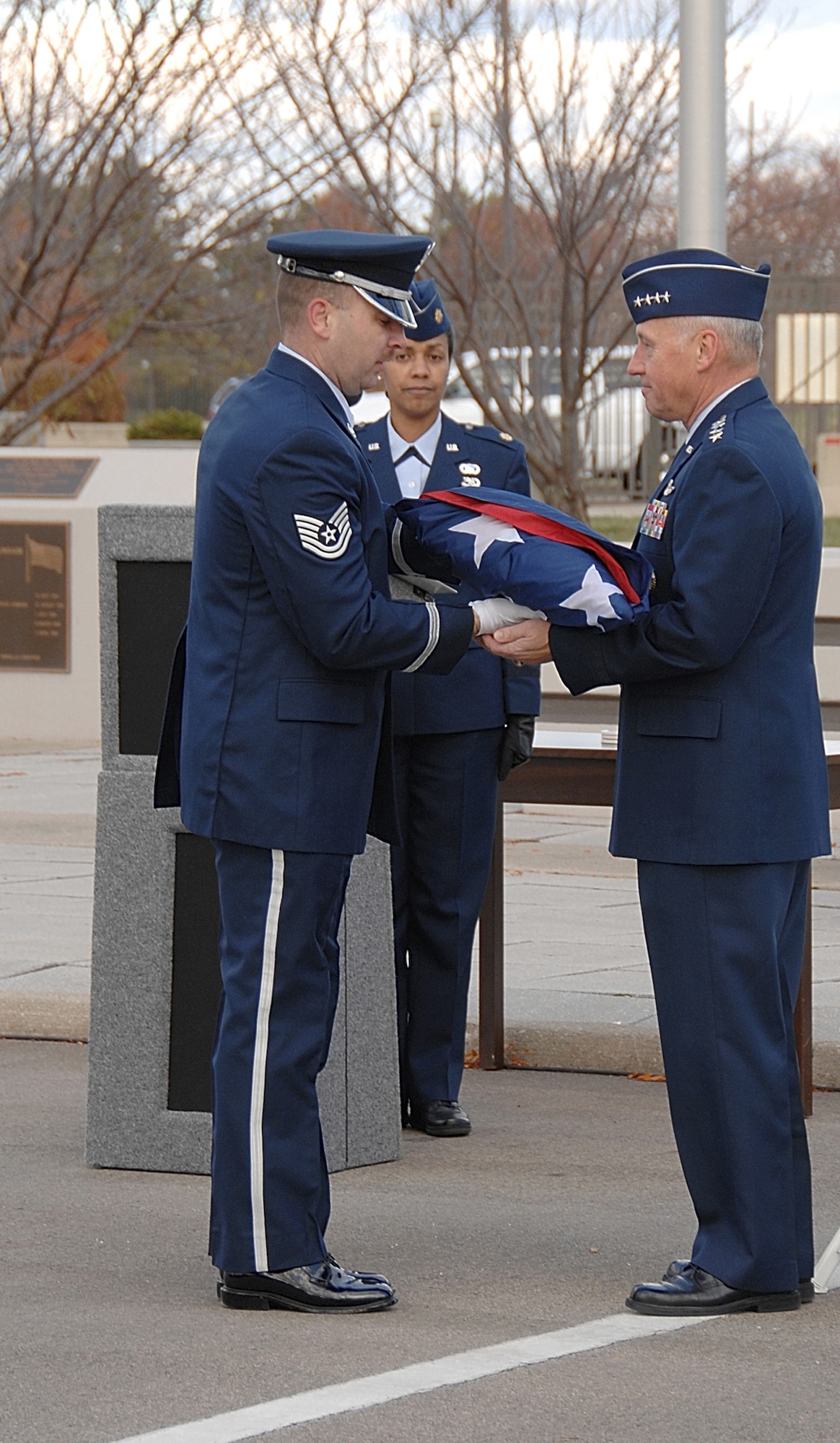 WRIGHT-PATTERSON AIR FORCE BASE, Ohio — Tech. Sgt. James Carr (left), the noncommissioned officer in charge for the Wright-Patterson Air Force Base Honor Guard, presents the American flag to Gen. Bruce Carlson during a formal retreat ceremony in front of Headquarters Air Force Materiel Command Nov. 18. Hundreds of active-duty personnel and civilians attended the ceremony, which featured a mixed, four-ship flyover by F-15s and F-16s from Eglin AFB, Fla. General Carlson, the AFMC commander, was the guest of honor. He is retiring from the Air Force after 37 years of service. (Air Force photo by Ben Strasser)