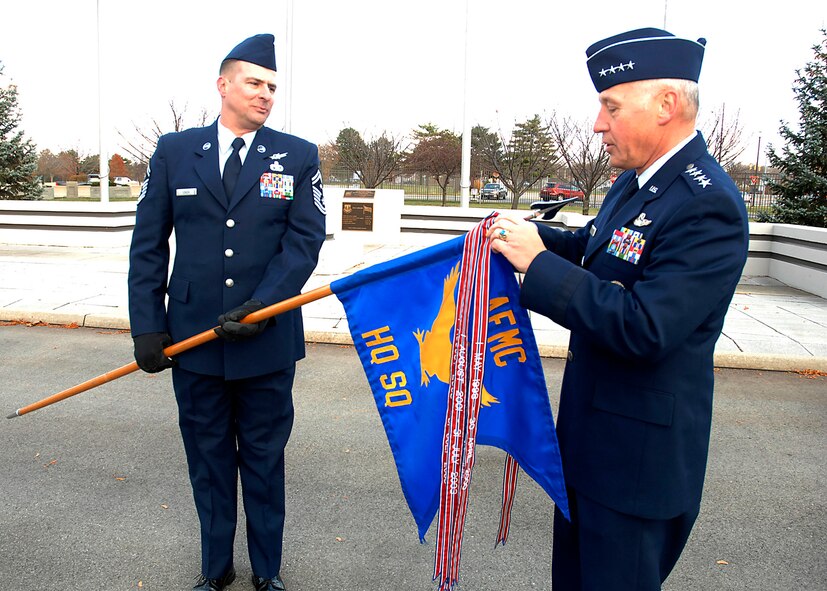 WRIGHT-PATTERSON AIR FORCE BASE, Ohio — Senior Master Sgt. Scott Leach, Headquarters Air Force Materiel Command first sergeant, lowers the organization’s guidon to allow Gen. Bruce Carlson, AFMC commander, to add the Air Force Organizational Excellence Award. It was part of a formal retreat ceremony that took place here Nov. 18 and featured a mixed, four-ship flyover by F-15s and F-16s from Eglin AFB, Fla. General Carlson, who was the guest of honor at the retreat, is retiring from the Air Force after 37 years of service. (Air Force photo by Al Bright)
