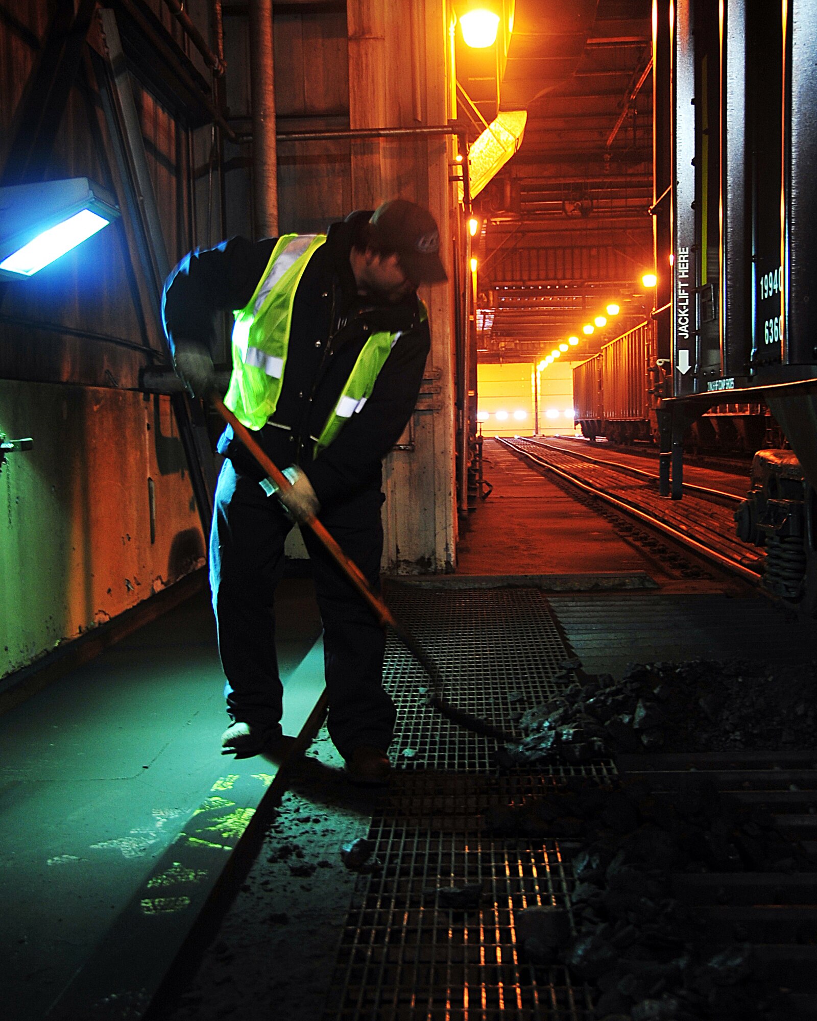 David Ritter, a coal and rail equipment operator feeds a WG-5701-08.  Mr. Ritter is shoveling spilled coal into the west grizzly hopper.  The coal is unloaded from rail cars into grizzlies, crushed and conveyed to the top of the plant where it is gravity fed into the boilers. (U.S. Air Force photo by Airman 1st Class Willard E. Grande II)