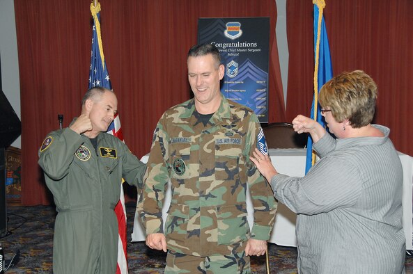 OFFUTT AIR FORCE BASE, Neb.--Senior Master Sgt. Andrew McCawley, U.S. Strategic Command, receives a traditional "tack on" from his wife Ylanda (right) and Brig. Gen. Mark Owen (left), U.S. Strategic Command, during the chief's promotion at the Patriot Club, Nov. 14. The rank of chief master sgt. is only attained by the top one percent of the U.S. Air Force's enlisted corps.  ( U.S. Air Force Photo By Dana Heard ) 