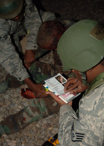 Staff Sgt Charles Jenkins, 49th Logistics Readiness Squadron, looks over his Airman's Manual as he administers self-aid and buddy care to a victim played by Senior Airman Jacob Johnson, 49th Aircraft Maintenance Squadron, at Holloman Air Force Base, N.M., Nov.17. Airman Petty and Sgt. Jenkins were doing post-attack reconnaissance for the phase II exercise, Cornet Gold Rush 08-08. (U.S. Air Force photo/Airman 1st Class Michael Means)