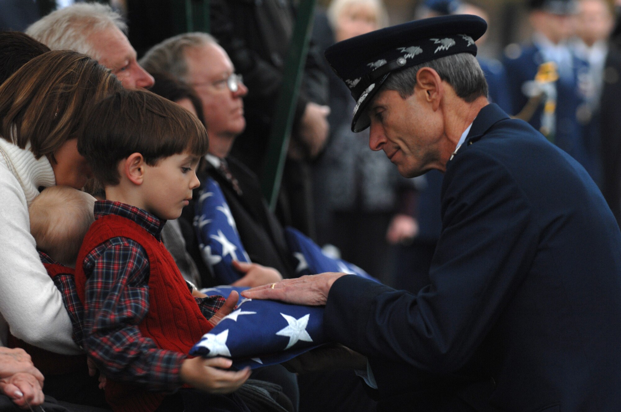 Gen. Norton Schwartz hands a folded American flag to one of the family members of the fallen B-52 Stratofortress crewmembers Nov. 14 at Arlington National Cemetery in Virginia. A group burial took place for six crewmembers of a B-52 that crashed off Guam's Northwest coast July 21. General Schwartz is the Air Force chief of staff. (U.S. Air Force photo/Staff Sgt. Catherine Thompson) 
