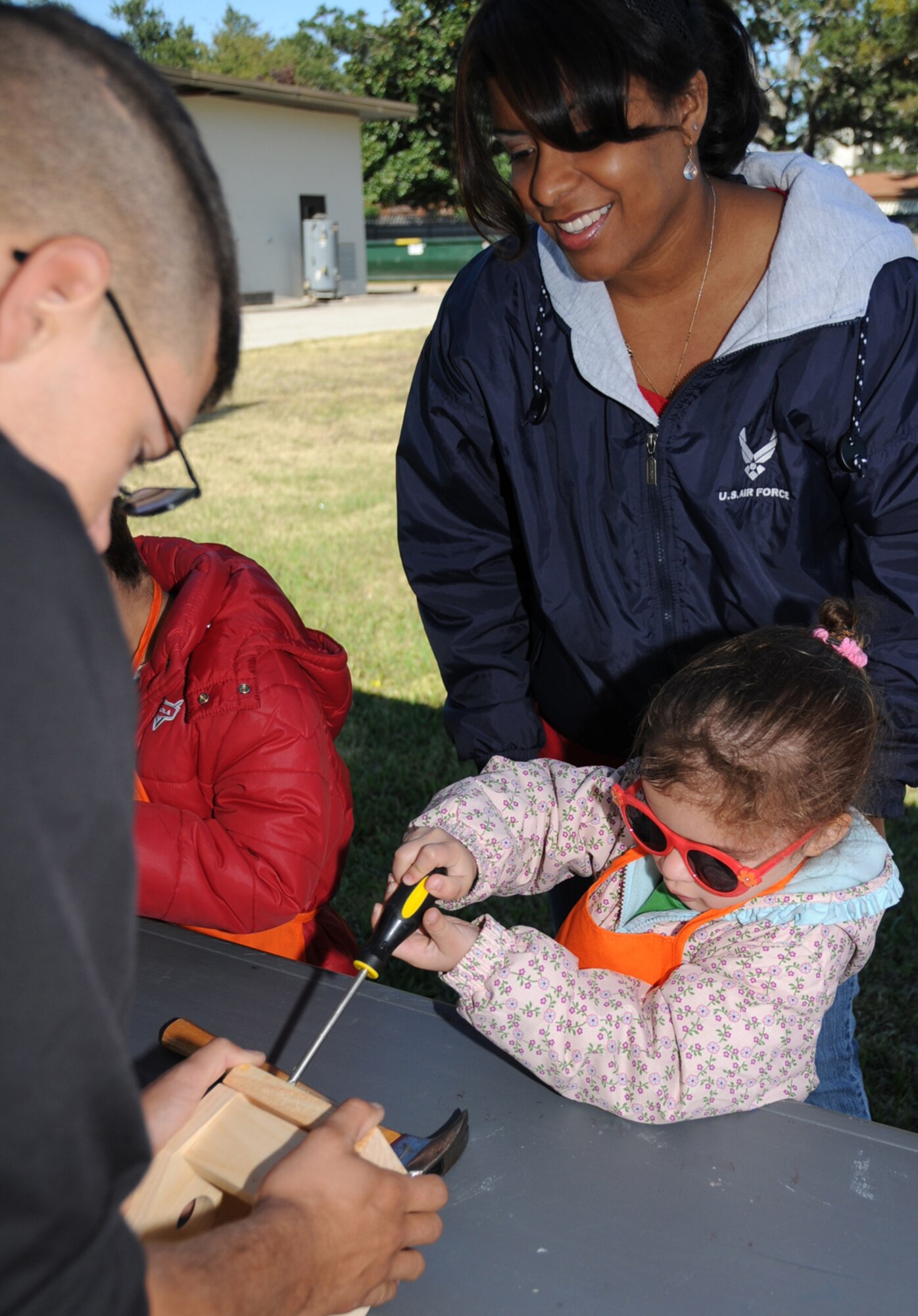 Pfc. Jonathan Gregory, left, Keesler Marine Corps Detachment, helps 4-year-old Hayley Hancock build a birdhouse at Saturday’s fall festival and holiday crafts fair as her mom, Argelia, looks on.  Hayley’s dad is Tech. Sgt. Lukus Hancock, 81st Surgical Operations Squadron.  (U.S. Air Force photo by Kemberly Groue)