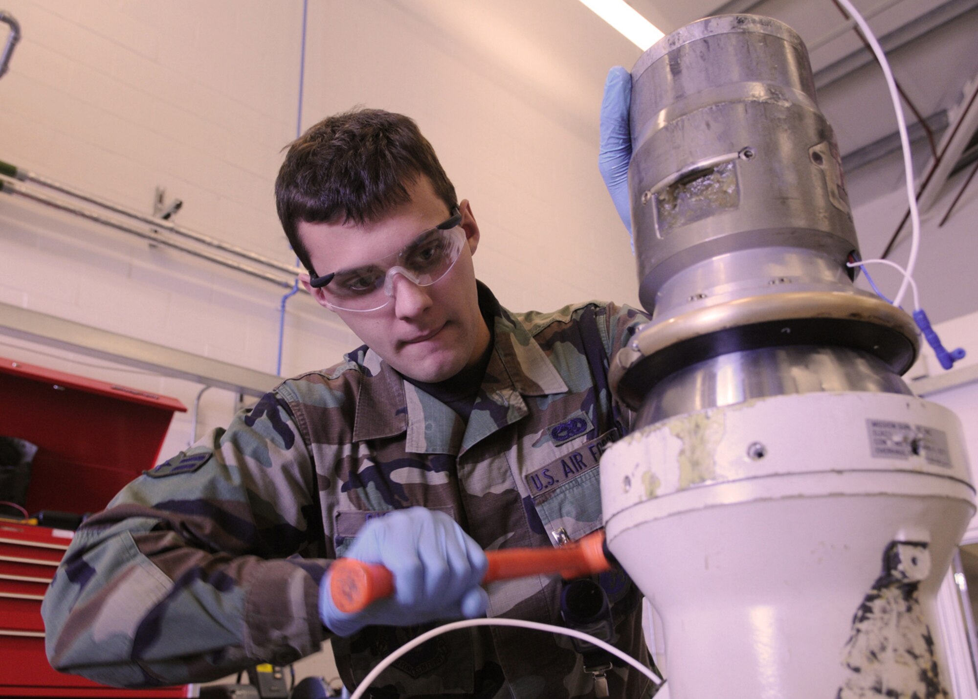 Airman 1st Class Robert Byers, a 100th Maintenance Squadron aircraft hydraulic apprentice, hammers a sleeve onto a refuel nozzle recently at RAF Mildenhall, England. Aircraft rely heavily on hydraulic power to operate properly, from extending the nozzle for aerial refueling to flap actuators that steer the aircraft in flight. Airmen in the hydraulic shop ensure all hydraulic components go through vigorous inspections and are fully functional before being released to any aircraft. (U.S. Air Force photo by Staff Sgt. Jerry Fleshman) 