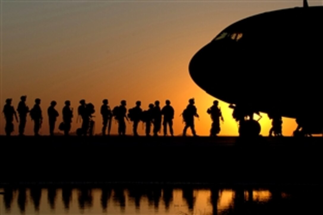 The sun sets behind a C-17 Globemaster III as U.S. Army soldiers wait in line to board the aircraft taking them back to the United States from Joint Base Balad, Iraq, Nov. 17, 2008. C-17s can carry payloads up to 169,000 pounds and can land on small airfields. 