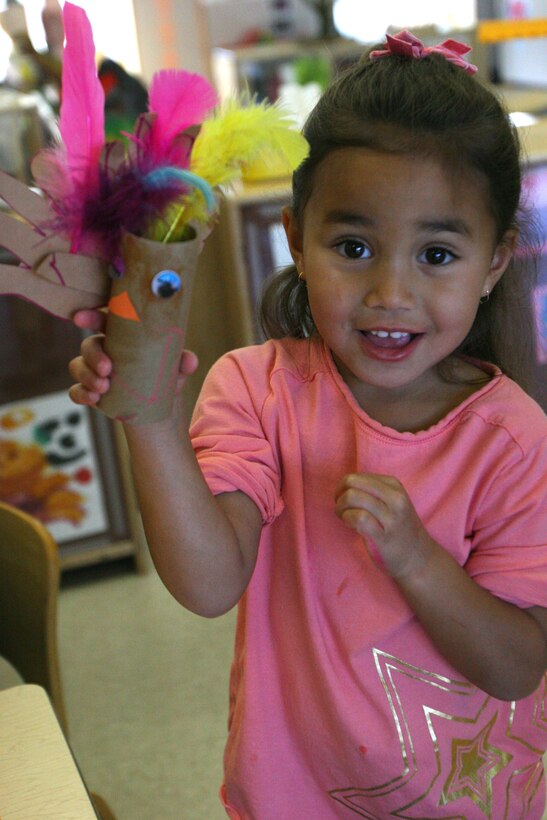 Cai Walker, a pre-school student at Stuart Mesa Child Development Center, proudly holds up her finished cardboard turkey. Cai put one blue and one pink eye on her turkey because they're her favorite colors.
