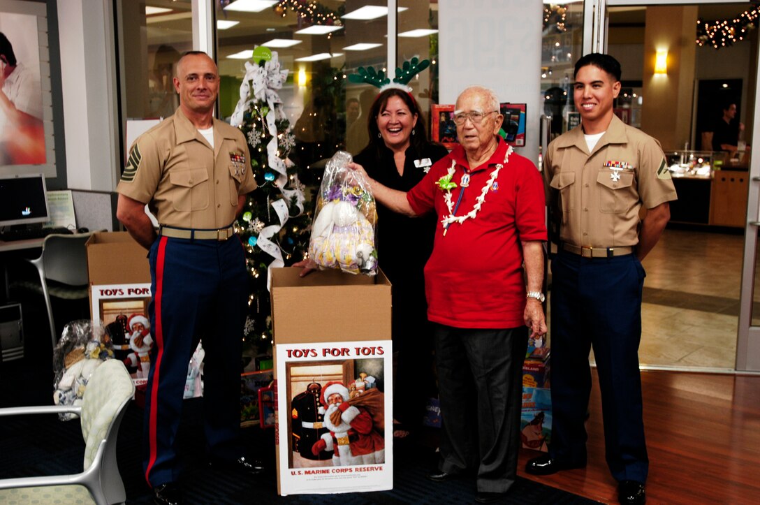(From left to right) 1st. Sgt. James Brown, Candice Nicholson, Hawaiian Telcom store manager, Ronald Oba, Army veteran and author of 'The Men of Company F' and Hawaiian Telcom customer, and Lance Cpl. Isaac K. Yuen, kicked off Hawaiian Telcom's participation in the annual Toys for Tots collection drive as Oba places a toy inside the drop box at the company's store in the Pearlridge Shopping Center here Nov 19.