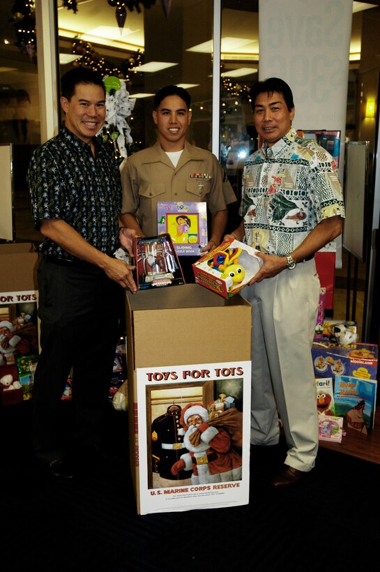 (From left to right) Geoff Loui, senior vice president of Strategy and Marketing, Lance Cpl. Isaac K. Yuen, Craig Inouye, senior vice president of sales display some toys that were collected by the Hawaiian Telcom employees Nov. 19 at the Pearlridge Shopping Center.  Hawaii Telcom has eight locations in Hawaii for people to drop off new, unwrapped toys to support the Toys for Tots program.