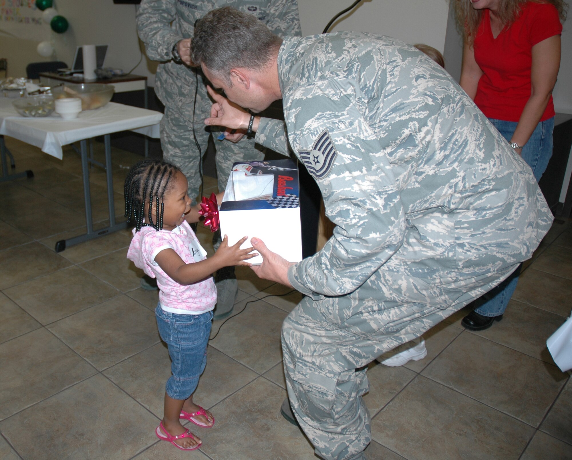Aniya Austin receives a gift from Tech. Sgt. Donovan Kohls, 944th Fighter Wing chaplain assistant, at the Deployed Spouses' Dinner Nov. 13 at the Luke Community Chapel.  The monthly dinner is done in an effort to recognize families while military members are deployed.  (U.S. Air Force photo/Staff Sgt. Denise Willhite)