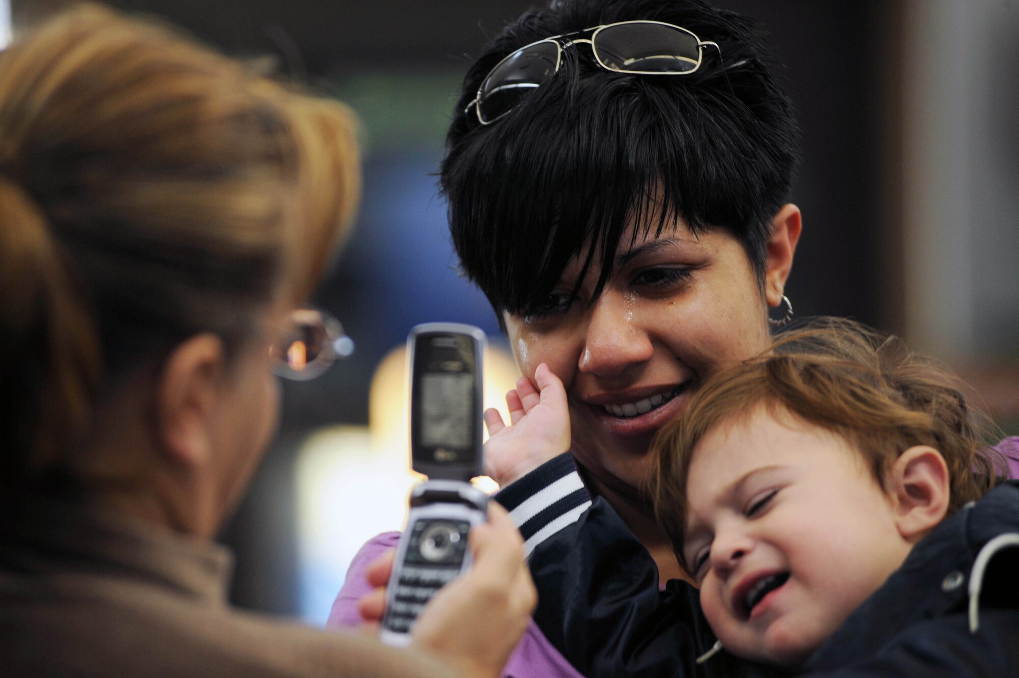 Senior Airman Angela Gomez, 28th Security Forces Squadron leader, and son, Alexander, get their photo taken from a cell phone by Airman Gomez's mother, Isabel Aguilera, before Airman Gomez leaves for a deployment to Southwest Asia from Rapid City Regional Airport in Rapid City, S.D., Nov. 19. The Ellsworth security forces contingent will support Operation Iraqi and Enduring Freedom throughout Southwest Asia. (US Air Force photo/Airman Corey Hook)