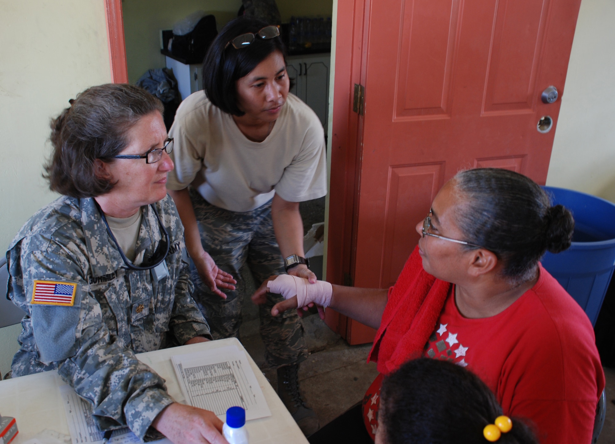 Army Maj. Nancy Gormley, a nurse from the JTF-Bravo Medical Element, and Air Force Staff Sgt. Kat Mansfield, an emergency medical technician, help a patient during a disaster relief medical mission Nov. 13 in Burrell Boom, Belize. More than 600 people were seen by U.S. and Belize military medical personnel in two different villages. 