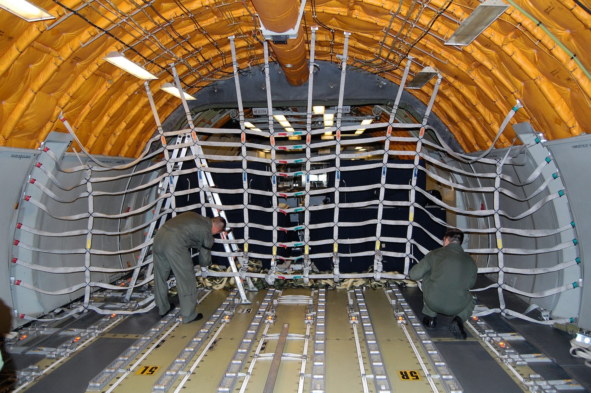 Boom operators from McGuire Air Force Base, N.J., install an alternative, lightweight cargo net inside a KC-10 Extender Sept. 16 as part of a demonstration for the Air Mobility Battlelab. The demonstration was for the battlelab's KC-10 Lightweight Cargo Net and Hoist Initiative which was recommended for use to Air Mobility Command. It was one of the last initiatives of the AMB, which deactivated Sept. 24 at the U.S. Air Force Expeditionary Center on Fort Dix, N.J. (U.S. Air Force Photo/Tech. Sgt. Scott T. Sturkol)