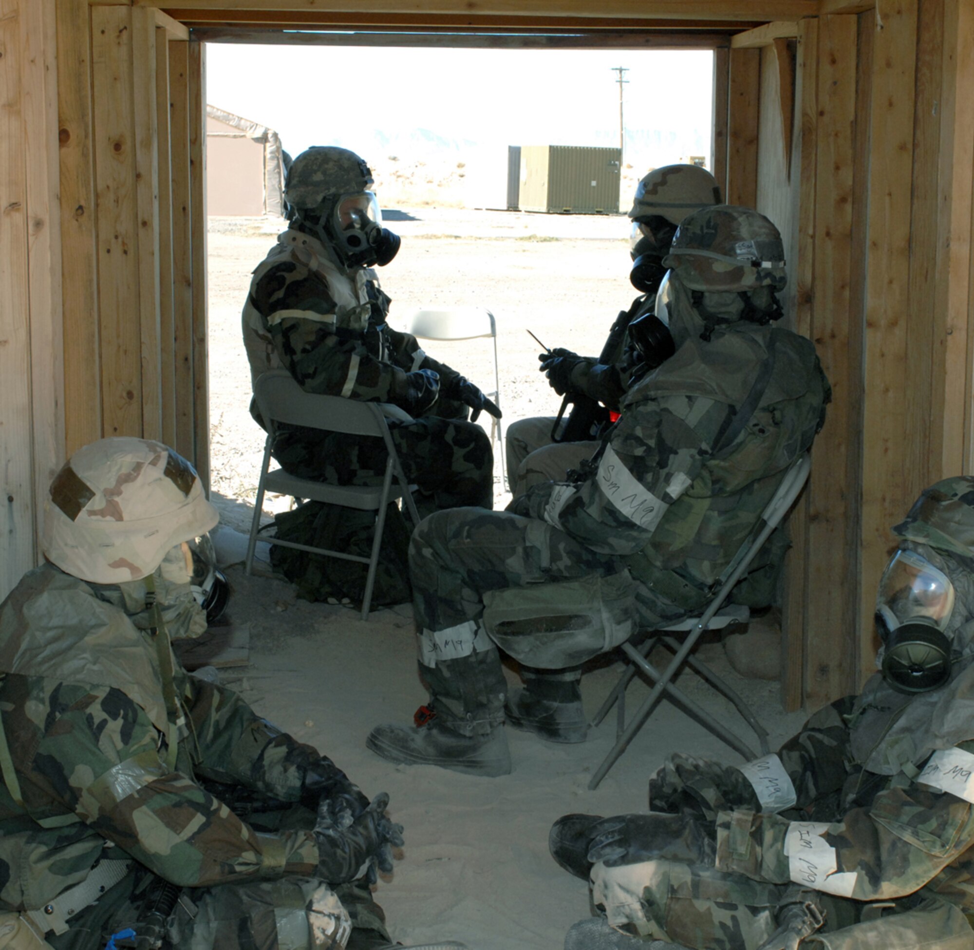 Members from the 49th Civil Engineer Squadron take shelter in a bunker during a simulated chemical attack at the CE pit during a phase II exercise at Holloman Air Force Base, N.M., Nov. 19. The Airmen are in full mission oriented protective posture (MOPP) 4, which includes a chemical suit, boots, gloves and gas mask. (U.S. Air Force photo/Airman Sondra M. Escutia)