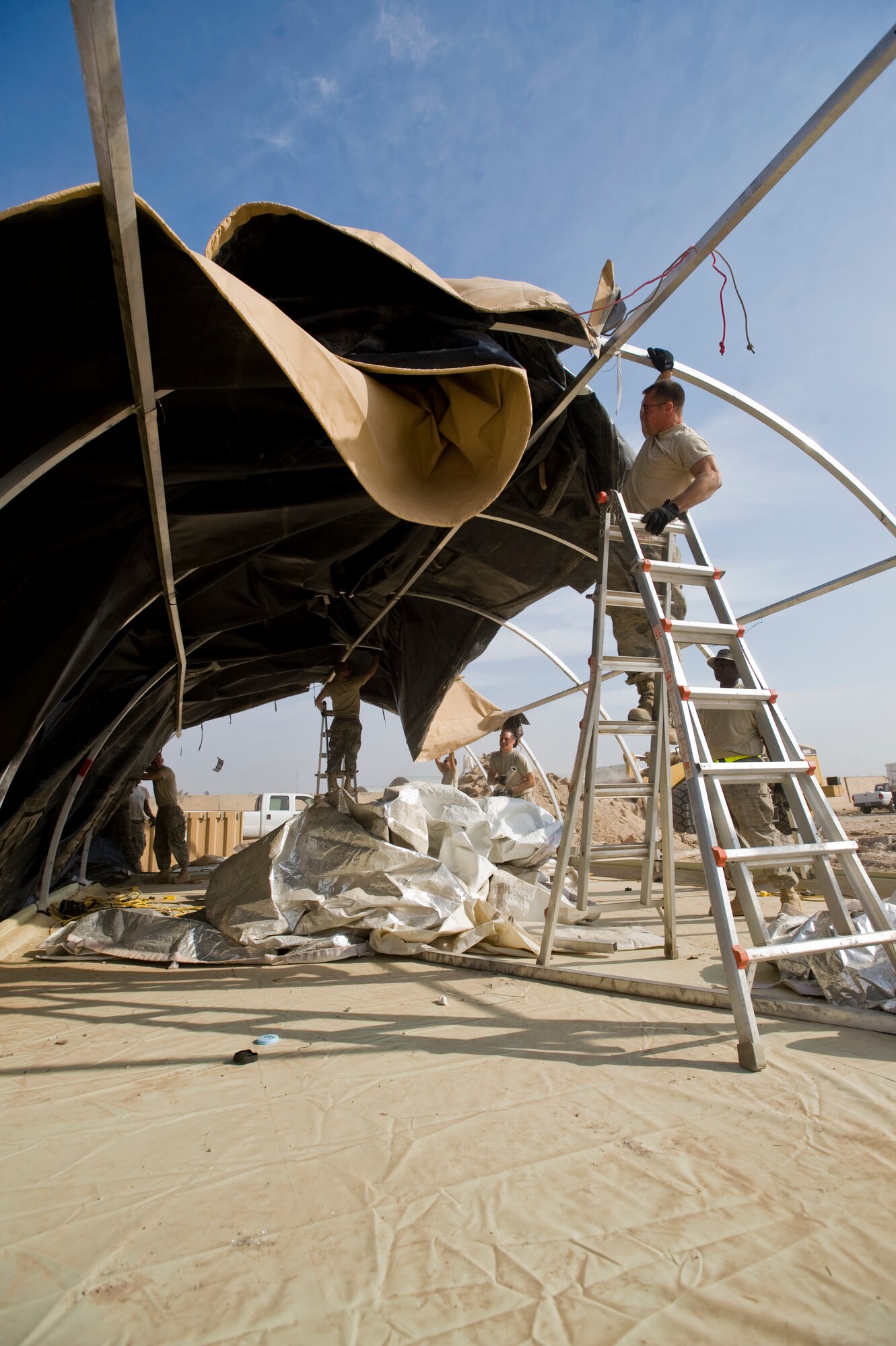 ALI BASE, Iraq -- Airmen from the 407th Expeditionary Civil Engineer Squadron pull the cover to an Alaskan shelter off of the supports Nov. 19, 2008. The 407th ECES Airmen improve living conditions by tearing down Alaskan shelters to make room for trailers which they will move into once completed. (U.S. Air Force photo/Senior Airman Christopher Griffin)