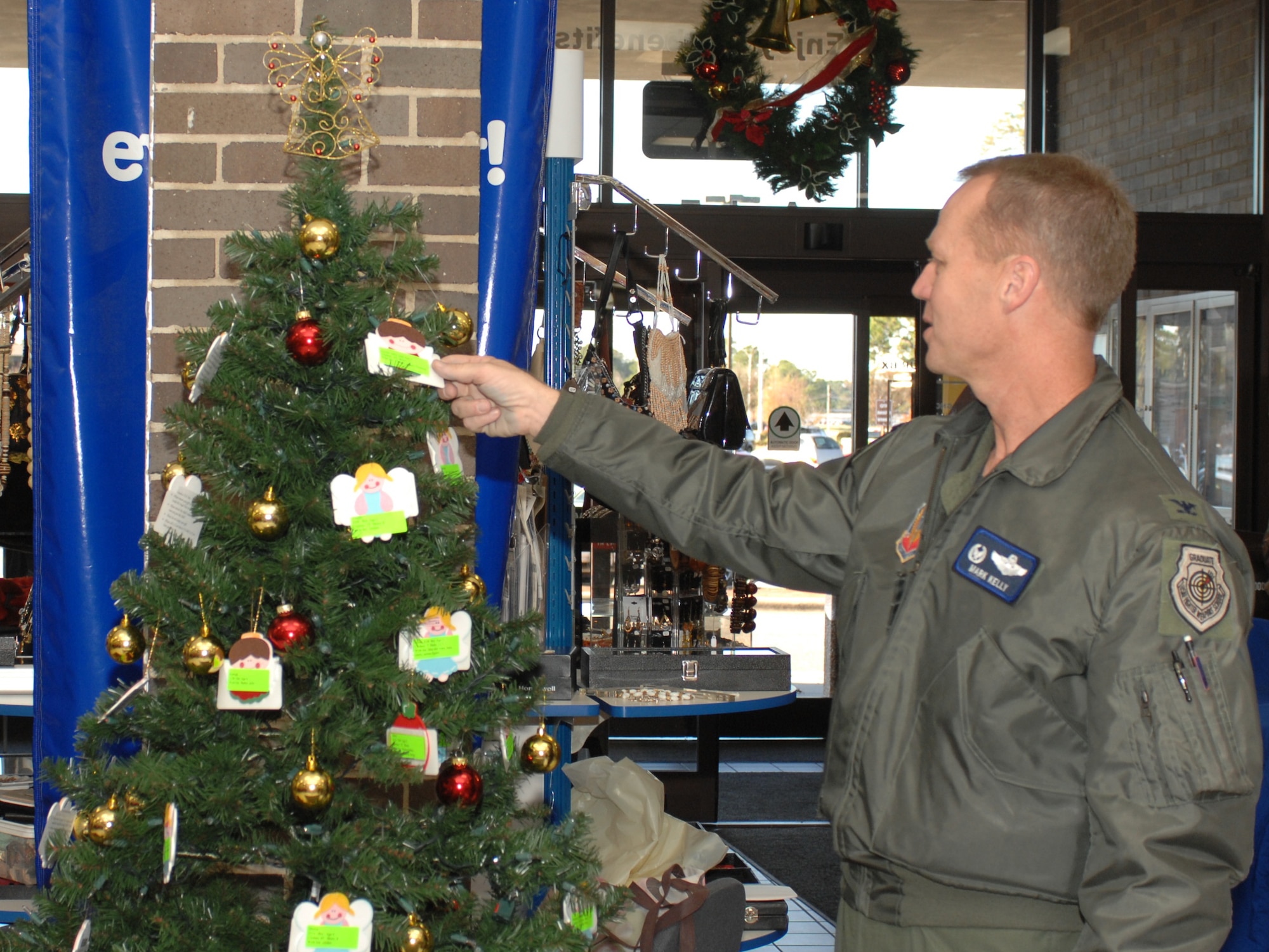 Base commander Col. Mark D. Kelly participates in the Angel Tree program at the entrance of the Base Exchange Nov. 19 at Seymour Johnson Air Force Base, N.C. The Angel Tree is a program created by the Salvation Army that provides clothes and shoes for children of needy families. People can pick an “Angel” from the tree, which contains the wish list of a base child, and take the unwrapped gifts to the sleigh at the Officers Club. 