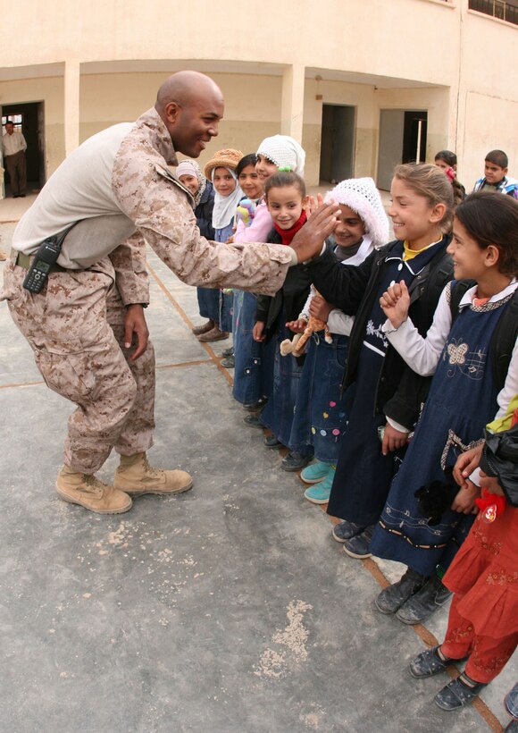 Second Lt. Dwayne Edwards, 26, a platoon commander with Company G, 2nd Battalion, 25th Marine Regiment, Regimental Combat Team 5, from New York City, exchanges high-fives with students at Ma'an Primary School in Rutbah, Iraq, Nov. 21.  In an effort to encourage community policing in the city, the Marines and Iraqi police officers distributed stuffed animals to the students and spoke to them about the United States and Iraq's joint commitment to the security of Iraq and development of the critical infrastructure.