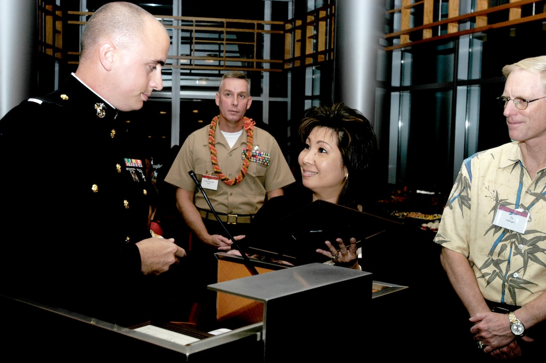 1st Lt. Luke Gaffney from 4th Force Reconnaissance Company presents a plaque to representatives from BAE Systems, Meadow Gold Diaries and First Hawaiian Bank for their corporate sponsorship of the Toys for Tots program.  More than 100 sponsor employees filled the 30th floor reception room at the First Hawaiian Administrative Headquarters building downtown.  This was the third year this event has been hosted by the program?s current corporate sponsors. Guests were encouraged to bring a new, unwrapped toy and were met at the door by Marines in dress blues.  The U.S. Marine Corps Forces, Pacific Band played a variety of songs throughout the evening as the guests were treated to pupus (hors d'oeuvres) and beverages.