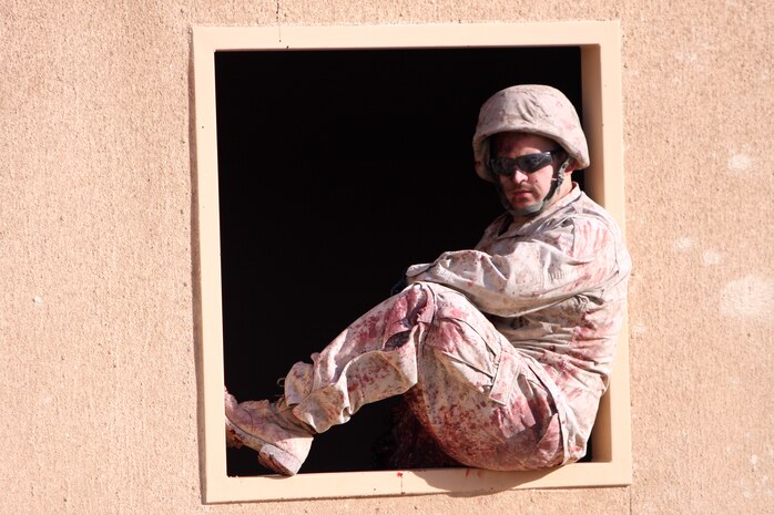 A Marine role player sits in a window as he waits for the next group of Marines to go through the medical lane during a Situational Training Exercise Nov. 20 and 21 on Range 220A aboard the Combat Center.  The medical lane trains Marines to take care of casualties while in a stressful combative environment.