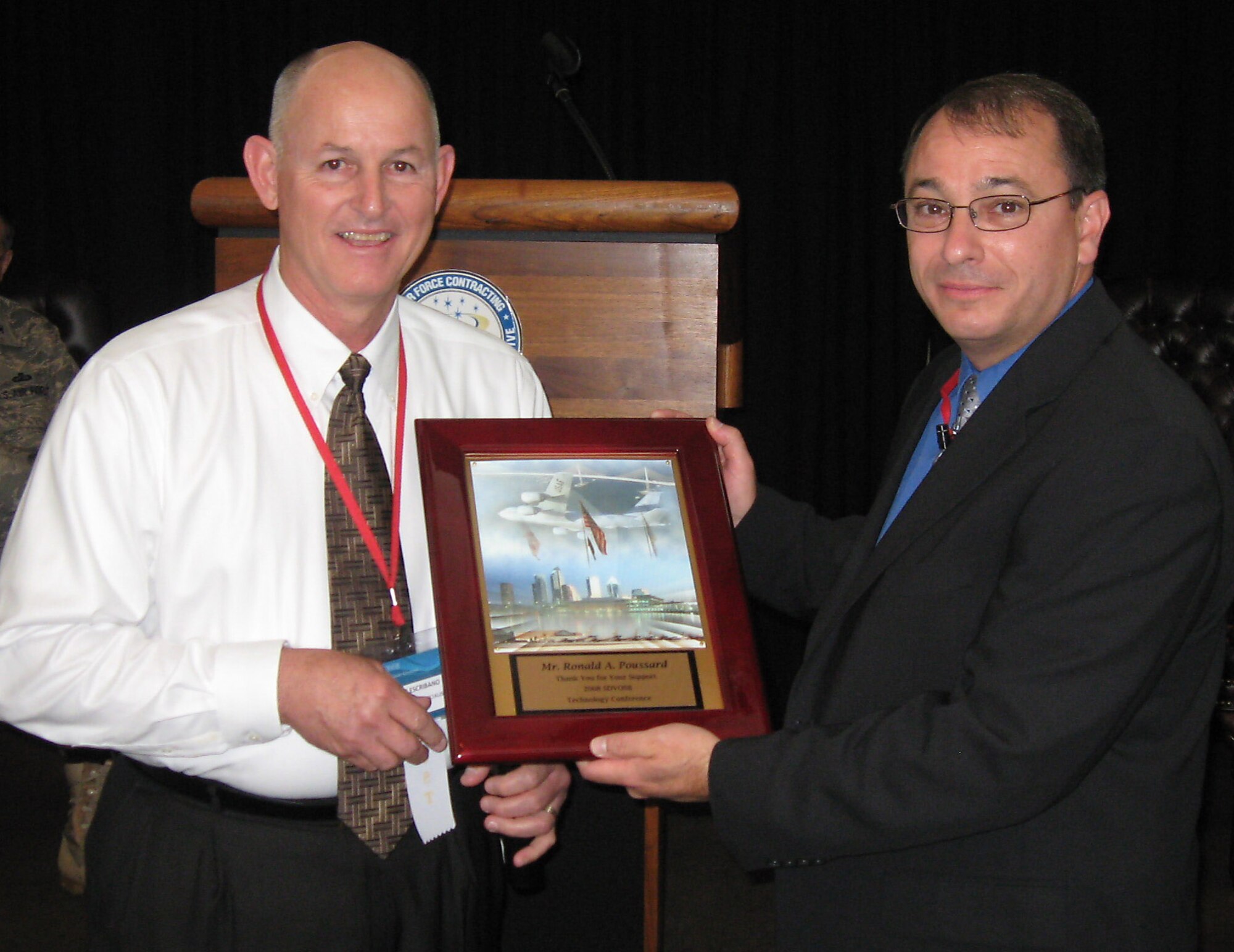 Ronald A. Poussard (right) receives a plaque from Nelson Escribano, at the 2008 Service-Disabled Veteran-Owned Small Business Technology Conference and Expo Nov. 13 at MacDill Air Force Base, Fla. Mr. Poussard is the director of the Secretary of the Air Force Small Business Programs. Mr. Escribano is a small business specialist for the 6th Air Mobility Wing at MacDill AFB. (Courtesy photo/CorpComm Inc.) 