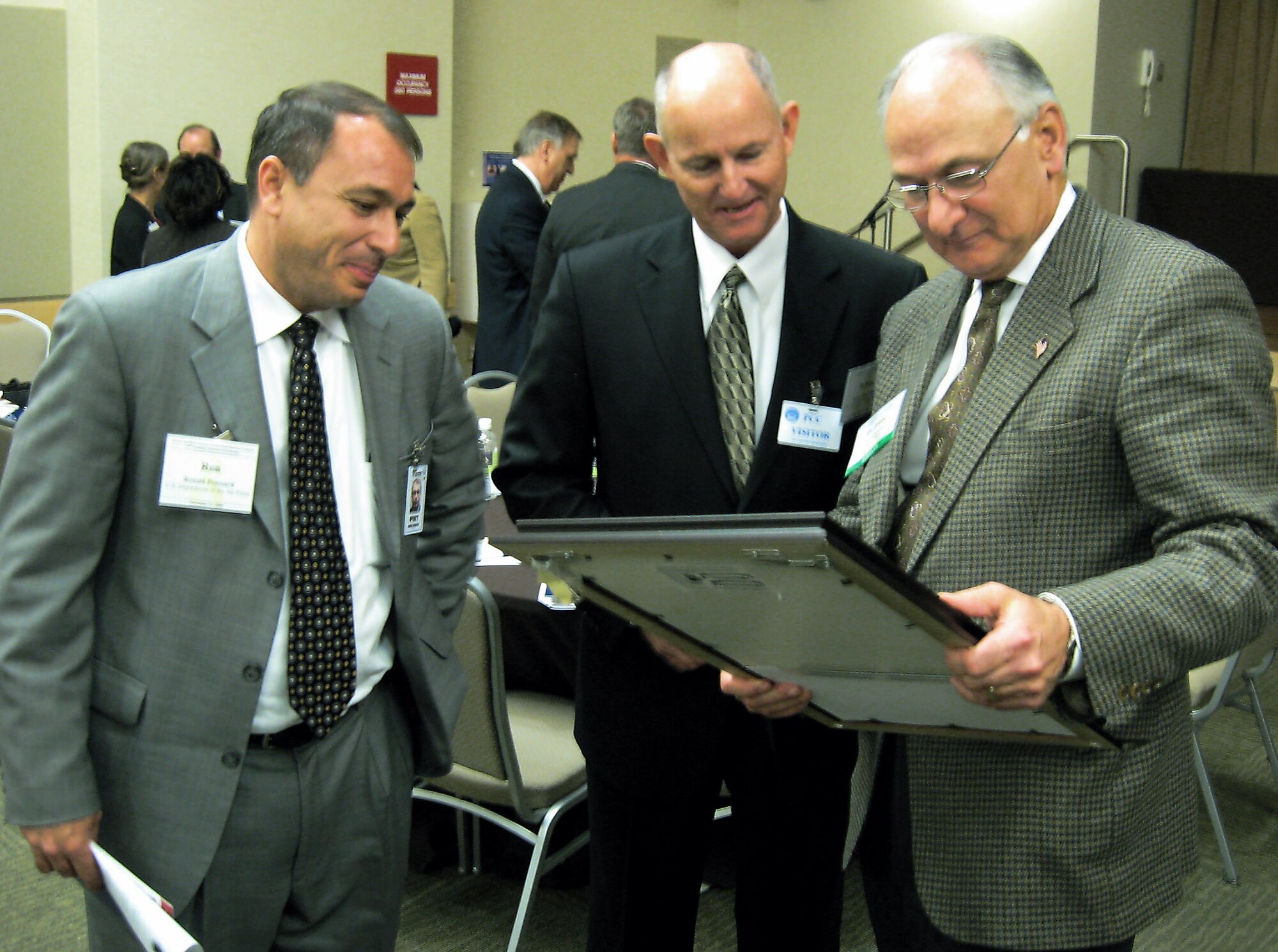 James I. Finley, deputy under secretary of defense for acquisition and technology, admires the Golden Talon Award which was presented to Nelson Escribano (center), small business specialist at the 6th Air Mobility Wing, MacDill Air Force Base, Fla., during the 2nd Annual Service-Disabled Veteran-Owned Small Business Awards Ceremony. At left is Ronald A. Poussard, the director of the Secretary of the Air Force Small Business Programs. The ceremony was held at the Pentagon Conference Center Nov. 17. (Courtesy photo/CorpComm Inc.)