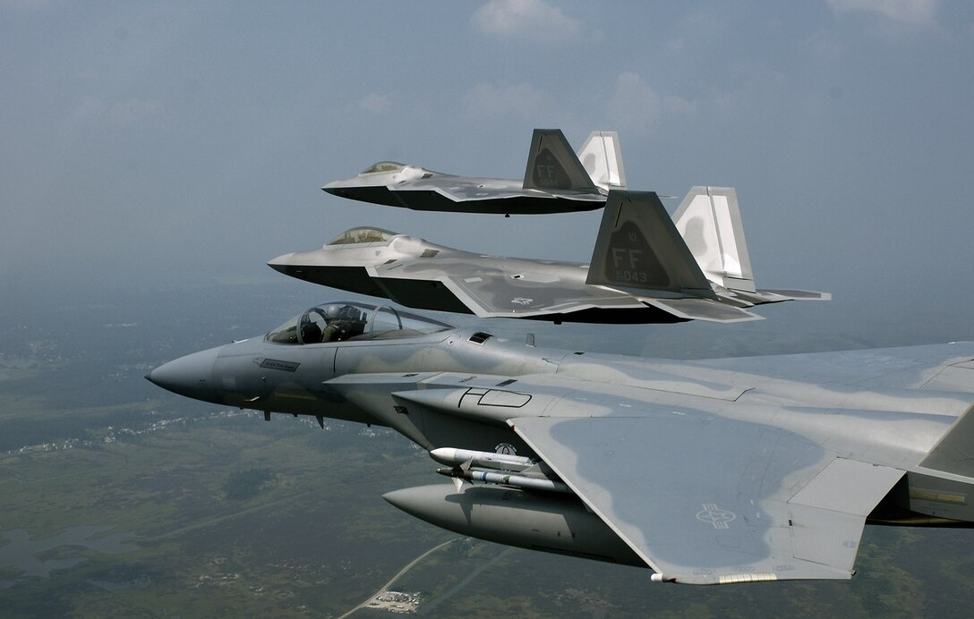 F-22 Raptors fly in formation with an F-15 Eagle. Defense Department officials are only partially funding the expansion of F-22 aircraft production, leaving the decision for further expansion to the incoming presidential administration. (U.S. Air Force photo/Tech. Sgt. Ben Bloker)

