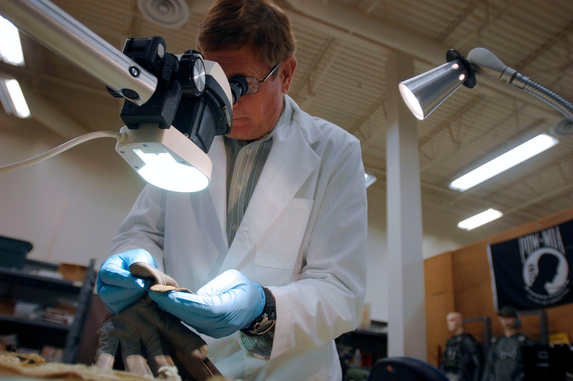Equipment Analyst Neill Smith inspects a glove sample recovered from an aircraft crash site in an attempt to identify the servicemember lost in the crash Nov. 4 at Brooks City-Base, Texas. The analysts at the Life Sciences Equipment Laboratory at Brooks City-Base in San Antonio use equipment at the lab as comparisons to the artifacts shipped to the lab from a recovery site. (Department of Defense photo/Fred W. Baker III) 
