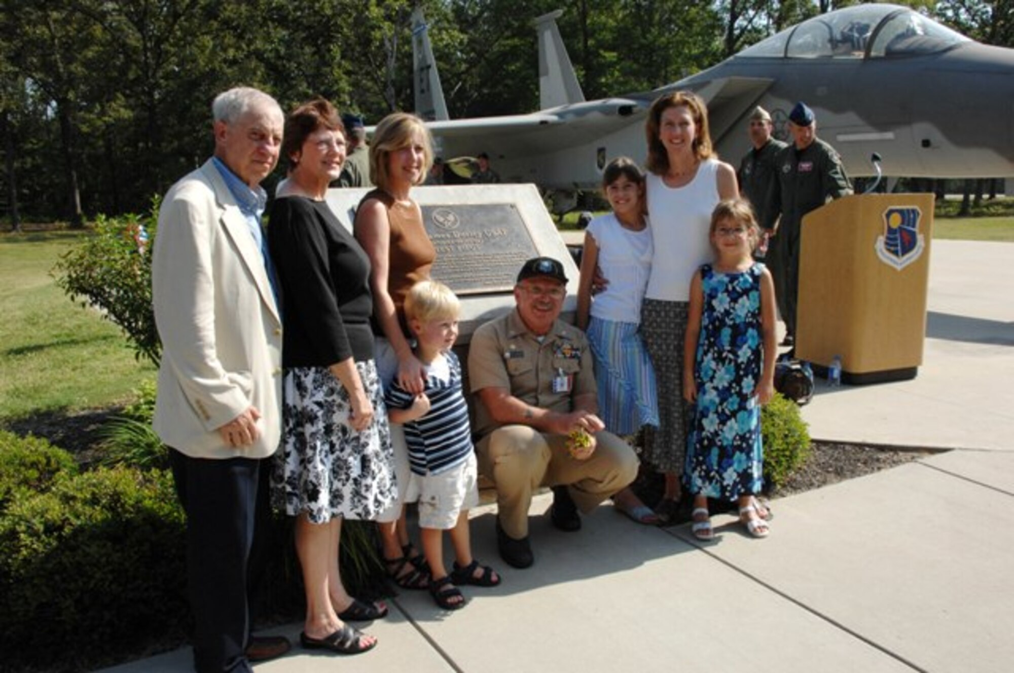 Navy Cmdr. Frank Moulds, 704th Maintenance Squadron commander, kneels with the family of Maj. James Duricy, who the F-15C Eagle static display here was dedicated to Aug. 9, 2007. (Photo by David Housch)