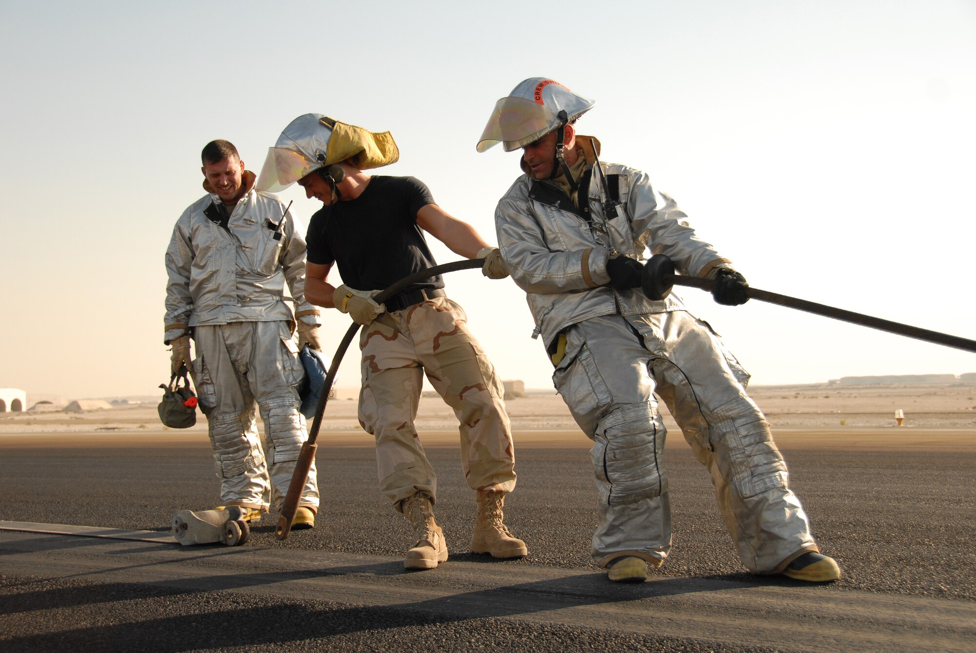 SOUTHWEST ASIA -- The 380th Expeditionary Civil Engineer Squadron's fire and emergency services crew, pull the pendant closer to the barrier tape so they could reconnect the two cables on the runway here Nov. 19. The pendant and barrier tape comprise the cable and straps used to catch the hook of a fighter jet landing or departing under emergency conditions. The team assisted in a cable engagement certification with the help of visiting F-15s from Eglin AFB, Fla. (U.S. Air Force photo by Tech. Sgt. Denise Johnson) (released)