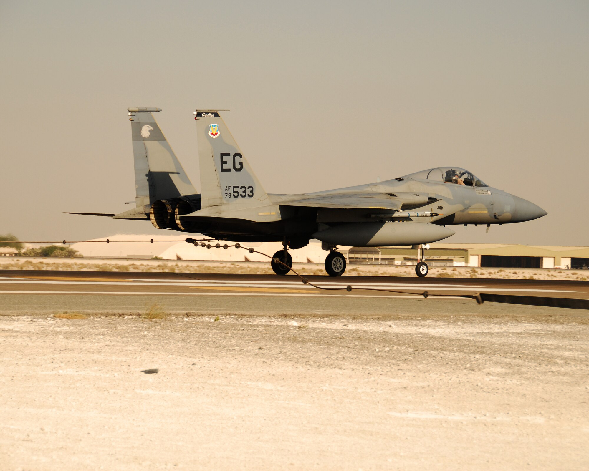 SOUTHWEST ASIA -- An F-15 hooks a barrier cable on the runway here Wednesday while 380th Expeditionary Civil Engineer Squadron fire and emergency service members stand watch. The 380th Air Expeditionary Wing took advantage of visiting aircraft from the 58th Fighter Squadron, Eglin Air Force Base, Fla., to conduct an operational inspection of the runway barriers here. (U.S. Air Force photo/Tech. Sgt. Denise Johnson) (Released)