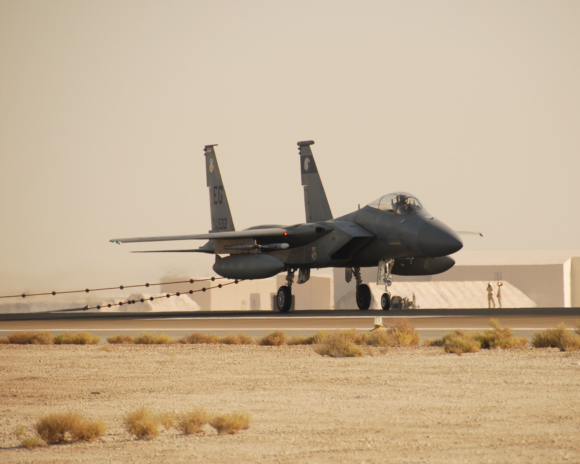 SOUTHWEST ASIA -- An F-15 hooks a barrier cable on the runway here Wednesday while 380th Expeditionary Civil Engineer Squadron fire and emergency service members stand watch. The 380th Air Expeditionary Wing took advantage of visiting aircraft from the 58th Fighter Squadron, Eglin Air Force Base, Fla., to conduct an operational inspection and certification of the runway barriers here. (U.S. Air Force photo/Tech. Sgt. Denise Johnson) (Released)