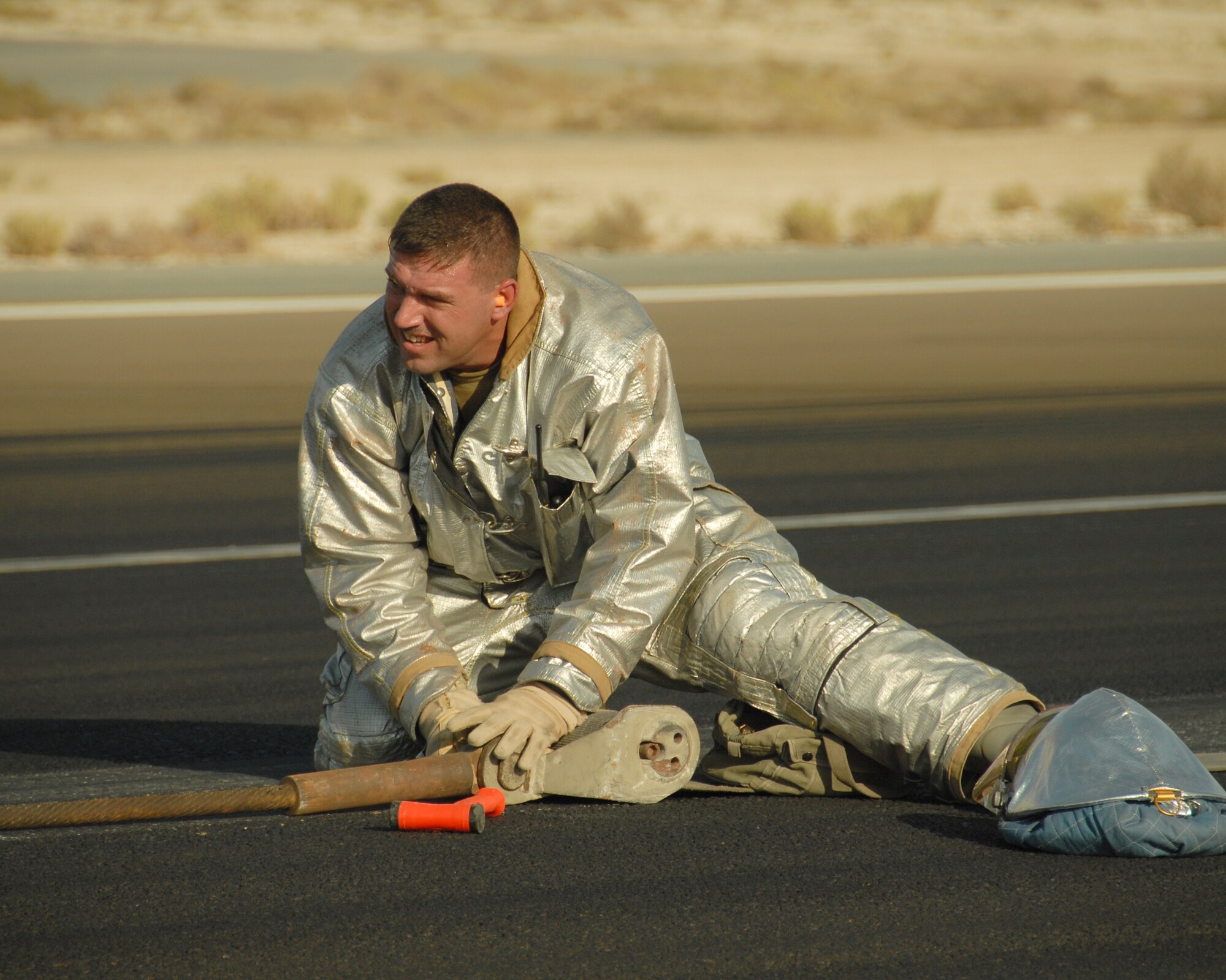 SOUTHWEST ASIA -- The 380th Expeditionary Civil Engineer Squadron's Tech. Sgt. Joshua Ashton, fire and emergency services station chief and rescue crew chief, removes the pin holding the pendant and the barrier tape together on the runway here Nov. 19. The pendant and barrier tape comprise the cable and straps used to catch the hook of a fighter jet landing or departing under emergency conditions. Sergeant Ashton, deployed from Andrews Air Force Base, Md., assisted in a cable engagement certification with the help of visiting F-15s from Eglin AFB, Fla. Sergeant Ashton is from Grove City, Ohio. (U.S. Air Force photo by Tech. Sgt. Denise Johnson) (released)