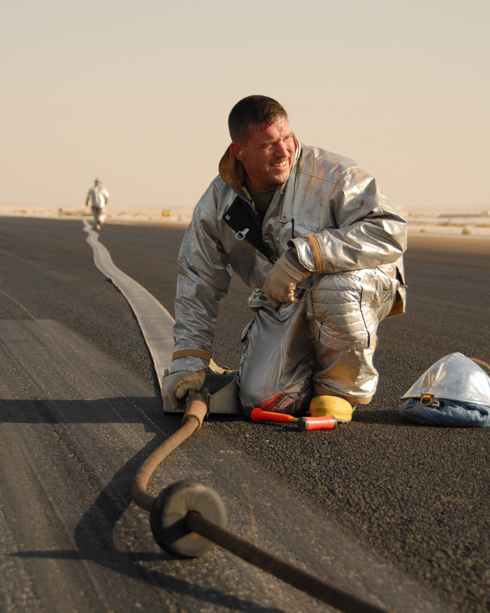 SOUTHWEST ASIA -- The 380th Expeditionary Civil Engineer Squadron's Tech. Sgt. Joshua Ashton, fire and emergency services station chief and rescue crew chief, removes the pin holding the pendant and the barrier tape together on the runway here Nov. 19. The pendant and barrier tape comprise the cable and straps used to catch the hook of a fighter jet landing or departing under emergency conditions. Sergeant Ashton, deployed from Andrews Air Force Base, Md., assisted in a cable engagement certification with the help of visiting F-15s from Eglin AFB, Fla. Sergeant Ashton is from Grove City, Ohio. (U.S. Air Force photo by Tech. Sgt. Denise Johnson) (released)