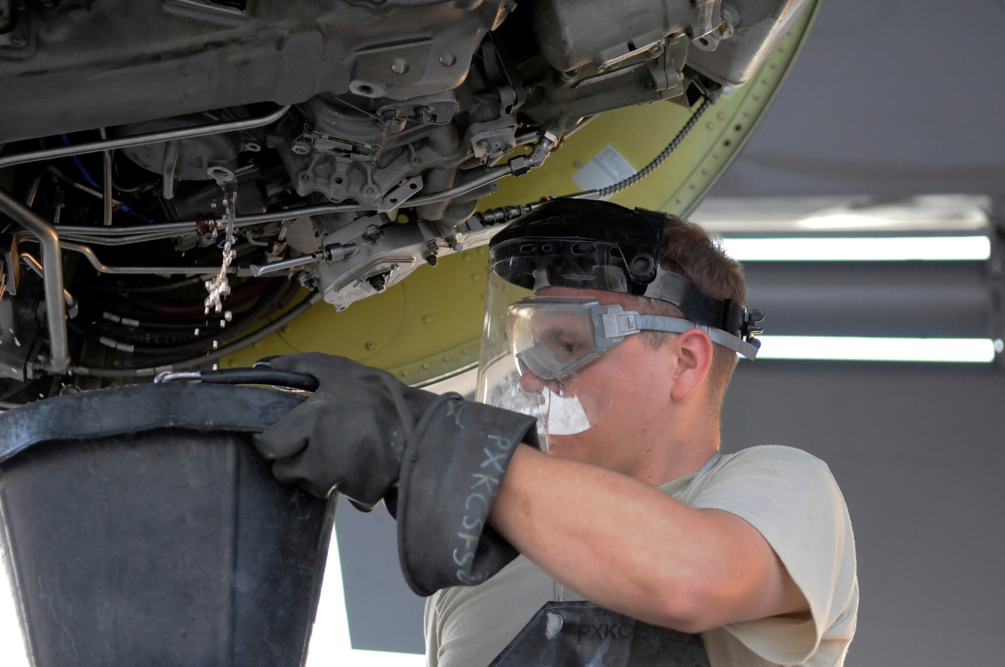 Staff Sgt. Anthony Hernandez, 379th Expeditionary Aircraft Maintenance Squadron, holds a bucket catching extra fuel after removing the fuel filter during a 120-hour inspection on a KC-135 Stratotanker engine, Nov. 20, at an undisclosed air base in Southwest Asia.   The KC-135 Stratotanker provides the core aerial refueling capability for the United States Air Force and also provides aerial refueling support to Navy, Marine Corps and allied nation aircraft in the Central Command area of responsibility.  Sergeant Hernandez is a native of Barstow, Calif., and is deployed from McConnell Air Force Base, Kan., in support of Operations Iraqi and Enduring Freedom and Joint Task Force-Horn of Africa.  (U.S. Air Force photo by Tech. Sgt. Michael Boquette/Released)