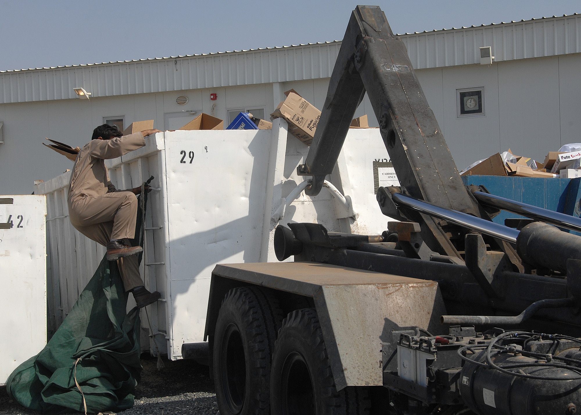 SOUTHWEST ASIA -- A recycling company worker prepares to cover and haul away a cardboard recycling bin on Nov. 15 at an air base in Southwest Asia. The 386th Air Expeditionary Wing recycles various items, to include cardboard boxes and plastic bottles. The money that is generated through the recycling program goes back to the base populace for quality of life initiatives and morale, welfare and recreation programs. (U.S. Air Force photo/Tech. Sgt. Raheem Moore)