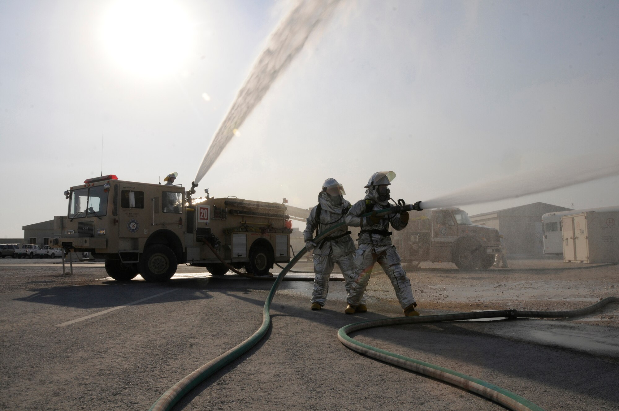 Senior Airman Nikolaus Sonksen, firefighter driver/operator, sprays a truck-mounted hose turret while Tech. Sgt. Peter W. Peterson, firefighter crew chief, and Airman 1st Class Zachary Kuiper, firefighter lineman, spray their hose in normal defensive attack as part of crew proficiency training Nov. 20, at an undisclosed air base in Southwest Asia. All are assigned to the 379th Expeditionary Civil Engineer Squadron. Daily crew proficiency training ensures these ECES members are prepared for any situation. Airman Sonksen, a native of Springville, Calif., is deployed from Travis Air Force Base, Calif. Sergeant Peterson, a native of Minneapolis, Minn., is deployed from Whiteman AFB, Mo.  Airman Kuiper, a native of Orlando, Fla., is deployed from Tyndall AFB Fla. All are deployed in support of Operations Iraqi and Enduring Freedom and Joint Task Force-Horn of Africa. (U.S. Air Force photo by Staff Sgt. Darnell T. Cannady/Released)