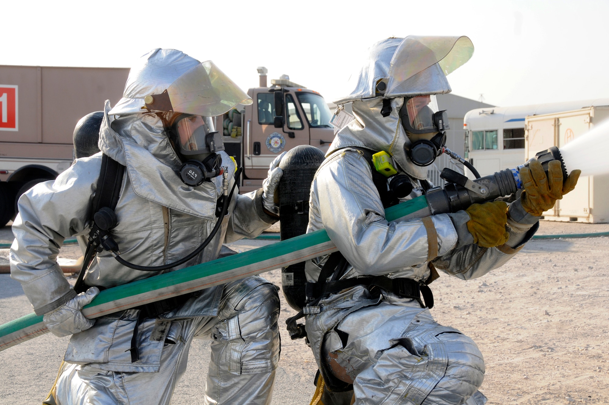 Tech. Sgt. Peter W. Peterson, firefighter crew chief, and Airman 1st Class Zachary Kuiper, firefighter lineman, both assigned to the 379th Expeditionary Civil Engineer Squadron, spray their hose in normal defensive attack as part of crew proficiency training Nov. 20, at an undisclosed air base in Southwest Asia. Daily crew proficiency training ensures these ECES members are prepared for any situation.  Sergeant Peterson, a native of Minneapolis, Minn., is deployed from Whiteman AFB, Mo., and Airman Kuiper, a native of Orlando, Fla., is deployed from Tyndall AFB Fla.  Both are deployed in support of Operations Iraqi and Enduring Freedom and Joint Task Force-Horn of Africa. (U.S. Air Force photo by Staff Sgt. Darnell T. Cannady/Released)