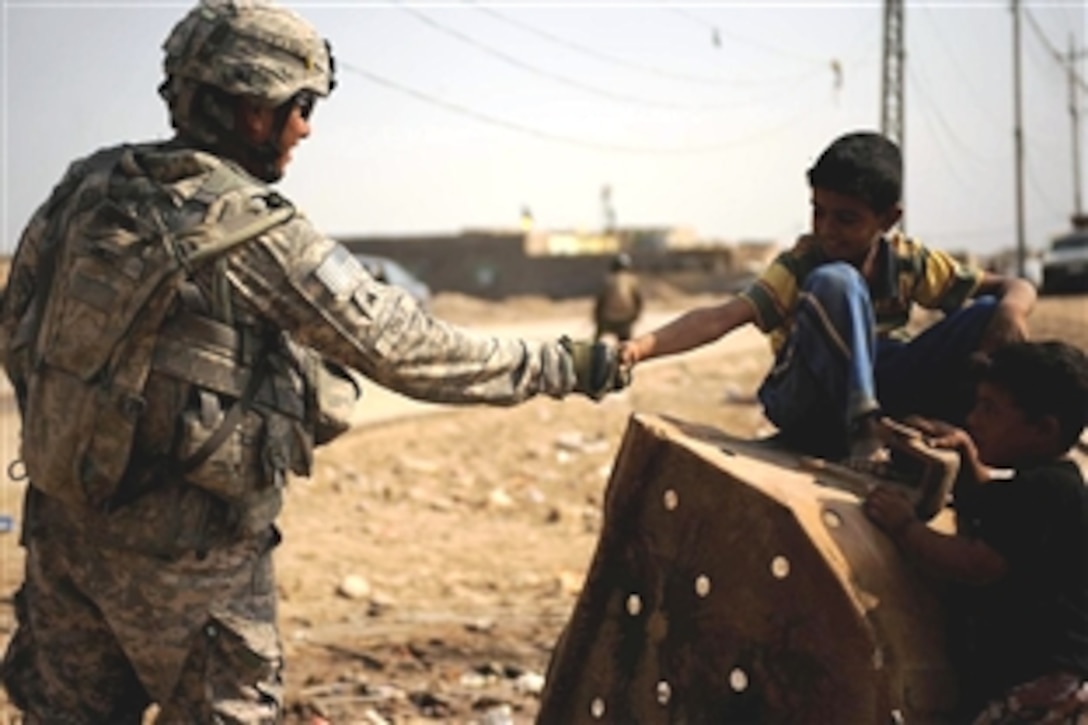 U.S. Army Sgt. Vinny Cruz shakes hands with an Iraqi boy during a patrol to assess the markets and needs of the people of Diwaniyah, Iraq, Nov. 13, 2008. Cruz and fellow soldiers are assigned to the 2nd Battalion, 8th Infantry Regiment, 2nd Brigade Combat Team, 4th Infantry Division.