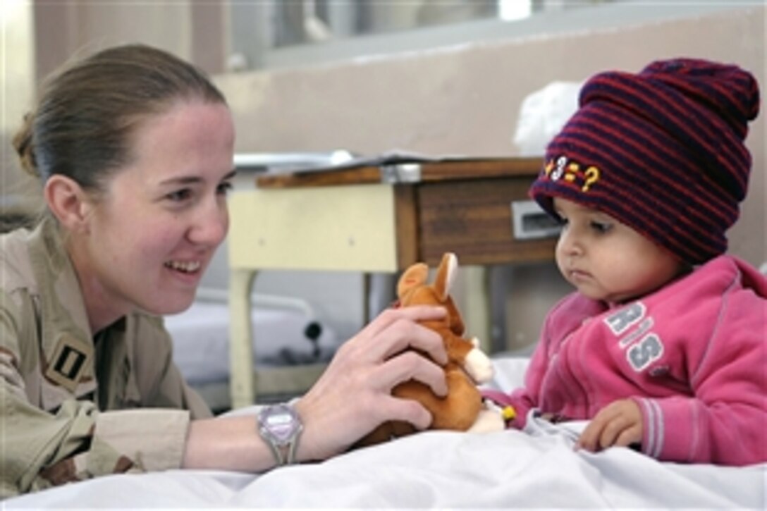 U.S. Navy Lt. Jessica Gandy, public affairs officer for the International Security Assistance Force, gives a stuffed kangaroo to cheer up an Afghan girl in the Indira Ghandi Children's Hospital Burn Ward, Kabul, Afghanistan, Nov. 20, 2008. International servicemembers assigned to ISAF gave stuffed animals and crayons to the children in the hospital.