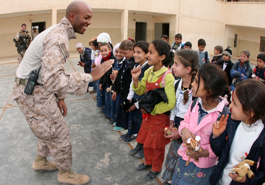Second Lt. Dwayne Edwards, 26, a platoon commander with Company G, 2nd Battalion, 25th Marine Regiment from New York City, exchanges high-fives with students at Ma'an Primary School here Nov. 20, 2008.  In an effort to encourage community policing in the city, the Marines and Iraqi police officers distributed stuffed animals to the students and spoke to them about the United States and Iraq's joint commitment to the security of Iraq and development of the critical infrastructure.