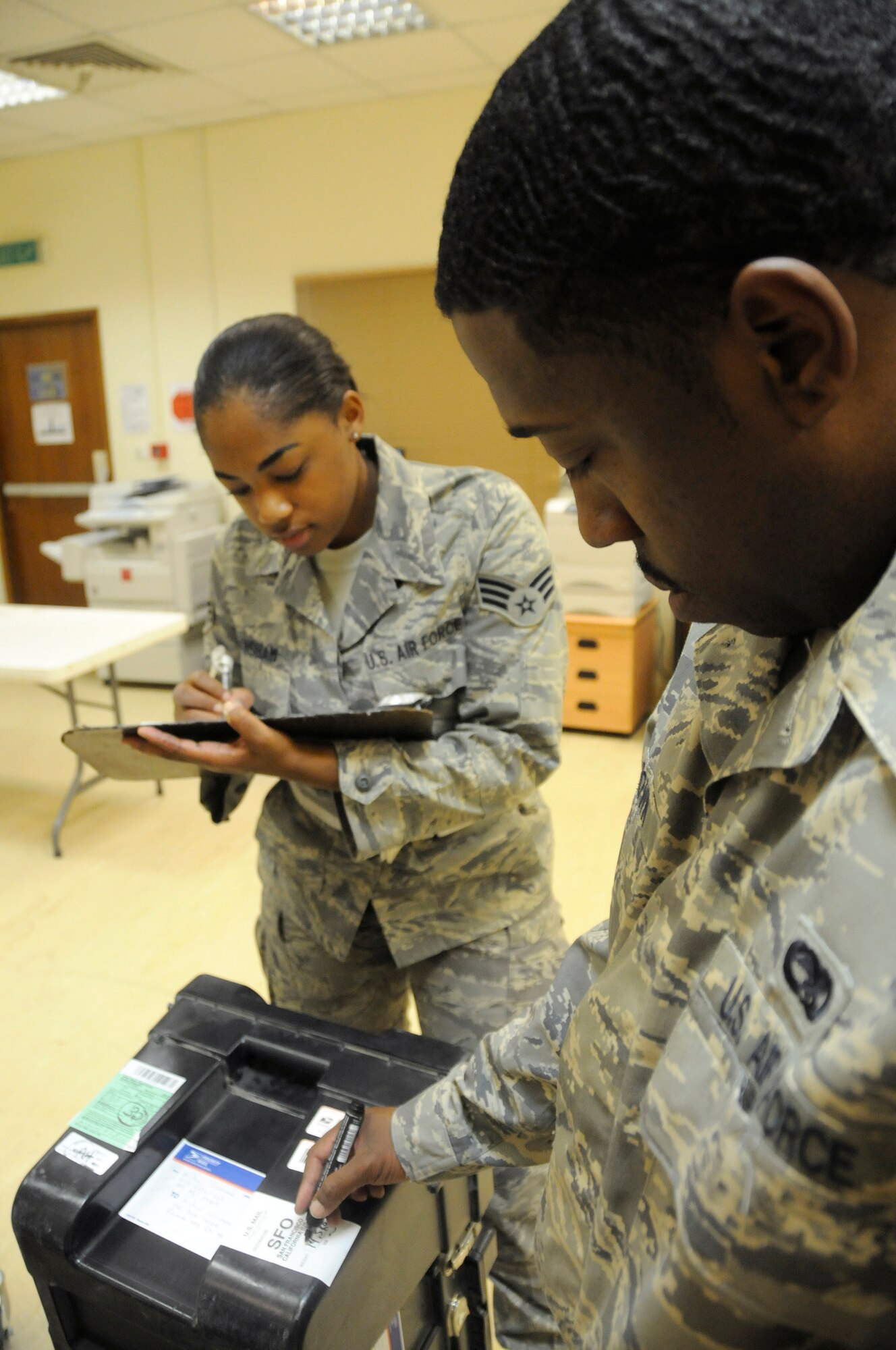 Senior Airman Ashley Hanshaw writes the weight onto a weight management sheet for manifest while Senior Airman Nimani Brown marks the weight on the package for outgoing mail Nov. 21, at an undisclosed air base in Southwest Asia. Both Airmen are postal specialists deployed to the 379th Expeditionary Communications Squadron in support of Operations Iraqi and Enduring Freedom and Joint Task Force-Horn of Africa. The ability to send and receive mail through the U.S. Postal System is an incredible morale boost for deployed members here.  Airman Hanshaw, a native of Bronx, N.Y., is deployed from Dobbins Air Reserve Base, Ga., and Airman Brown, a native of Chicago, Ill., is deployed from Ramstein Air Base, Germany.  (U.S. Air Force photo by Staff Sgt. Darnell T. Cannady/Released)