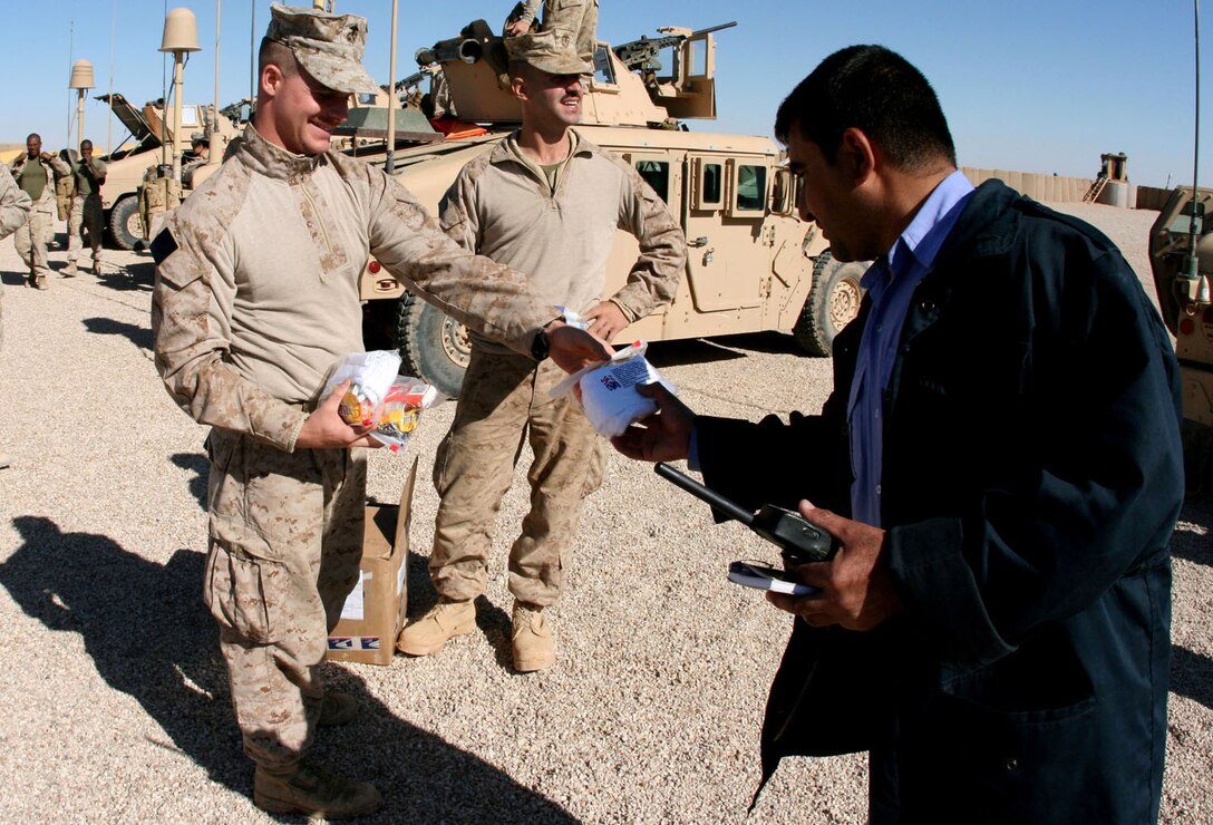 Sgt. Joseph Potucek (left), 25, of Nastic, N.Y., and Lance Cpl. Alexander Vassilopoulos, 27, from New York City, hand out packages of hygiene and comfort items to Iraqi highway patrolmen at an Iraqi base in Western al-Anbar province, Iraq, Nov. 23.  Both Potucek and Vassilopoulos are Reserve Marines with Weapons Company, 2nd Battalion, 25th Marine Regiment, Regimental Combat Team 5.  The packages were mailed to the Marines in Iraq by a women's organization in Carlsbad, Calif., to show their support for the troops' service in fighting the Global War on Terror.::r::::n::